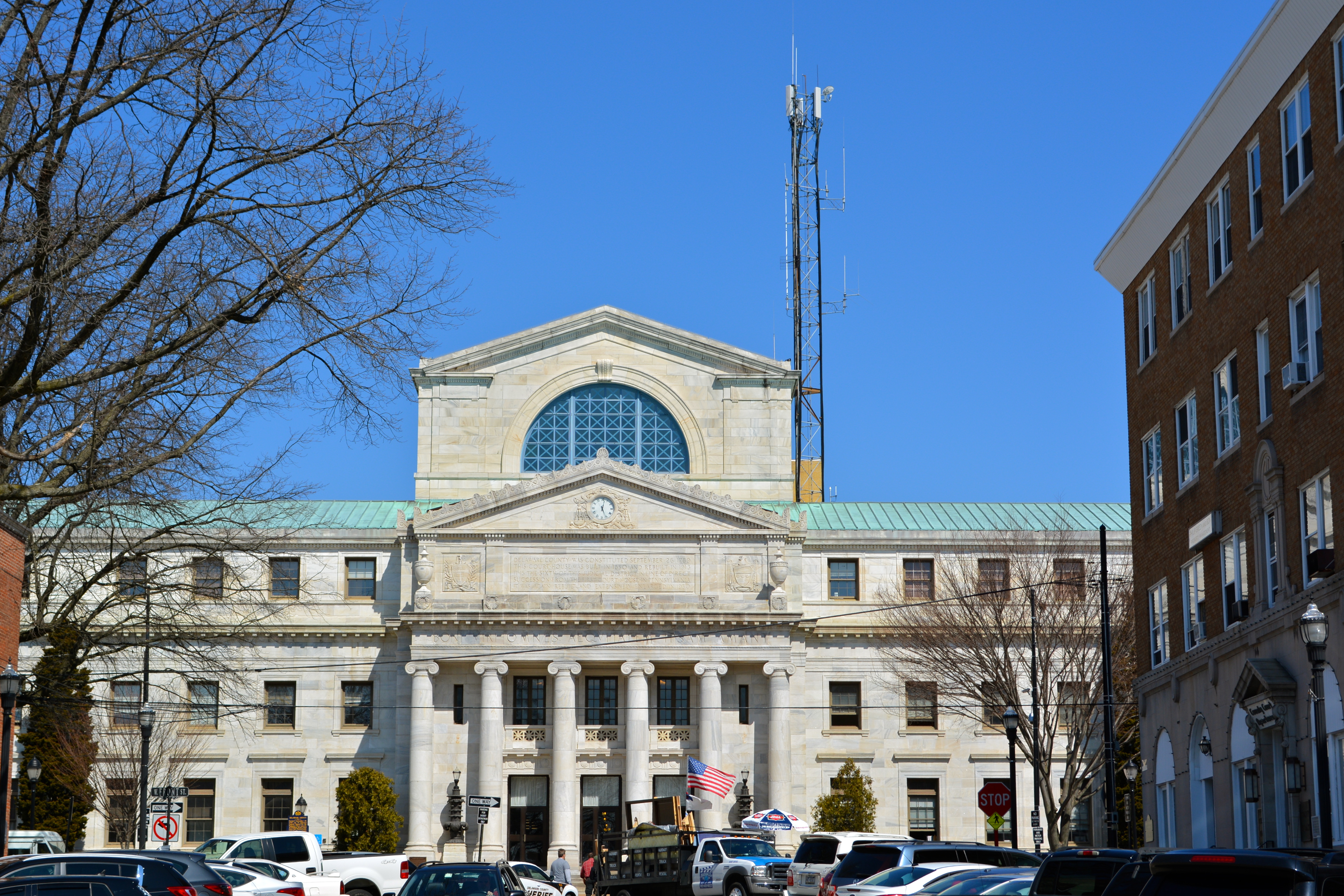 Neoclassical stone courthouse with large columns and green copper roof, flanked by bare trees.