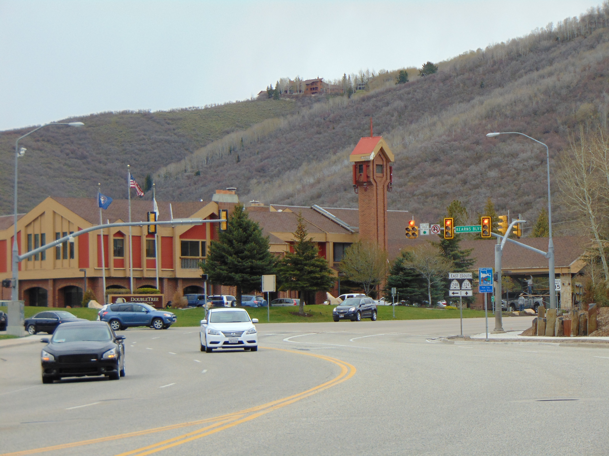 Multi-lane highway intersection with traffic signals and a hotel in the background.