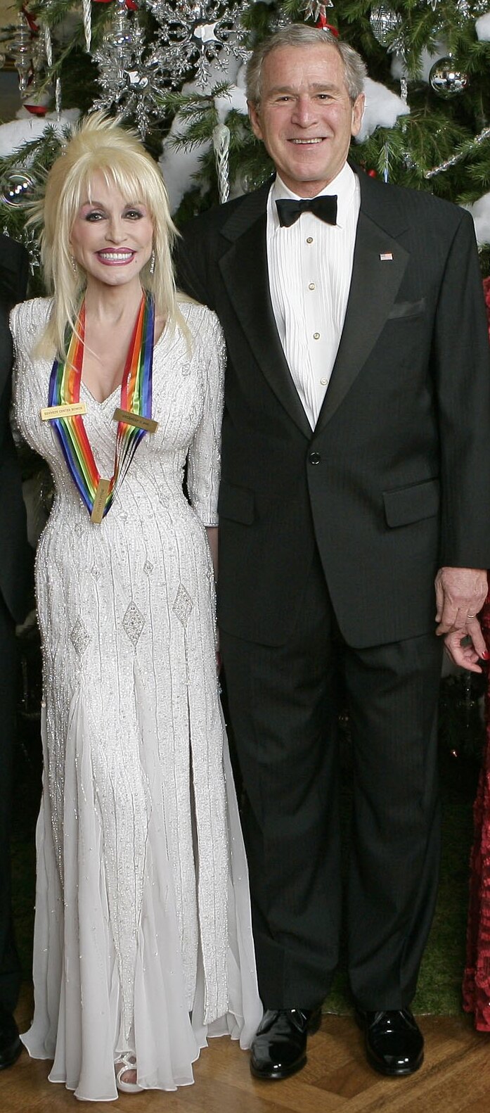 Woman in white beaded gown wearing a Kennedy Center Honors ribbon at a formal White House reception.