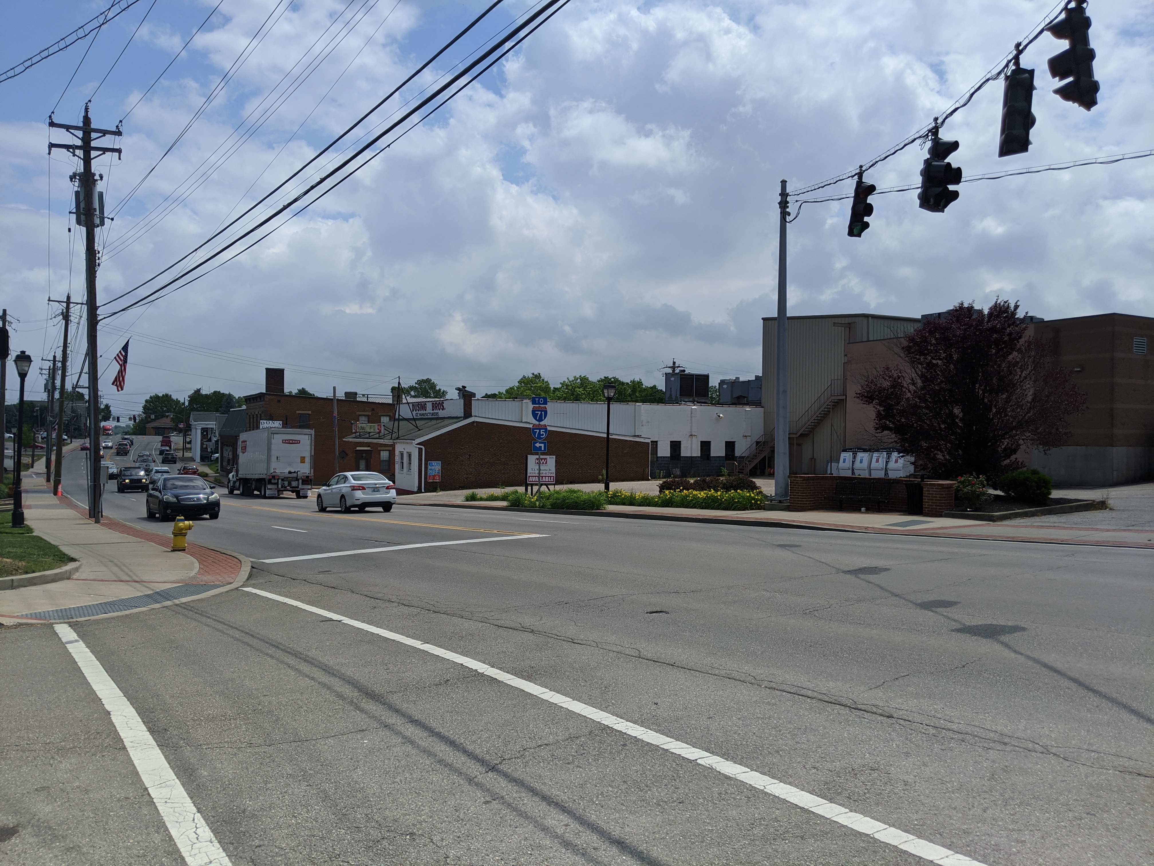 Multi-lane road with traffic signals and commercial buildings lining both sides.