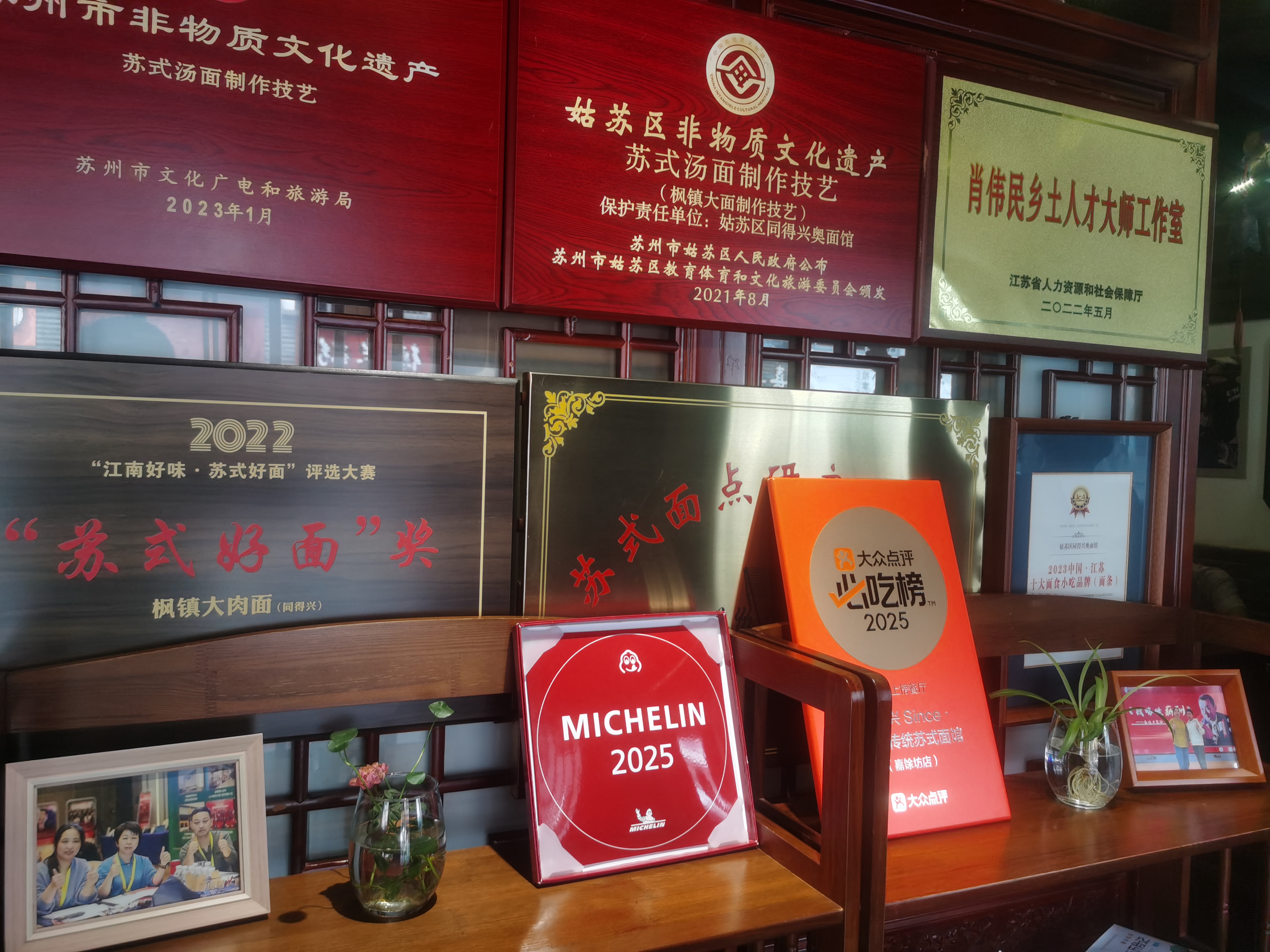A red Michelin 2025 award plaque displayed on a shelf among other restaurant accolades.