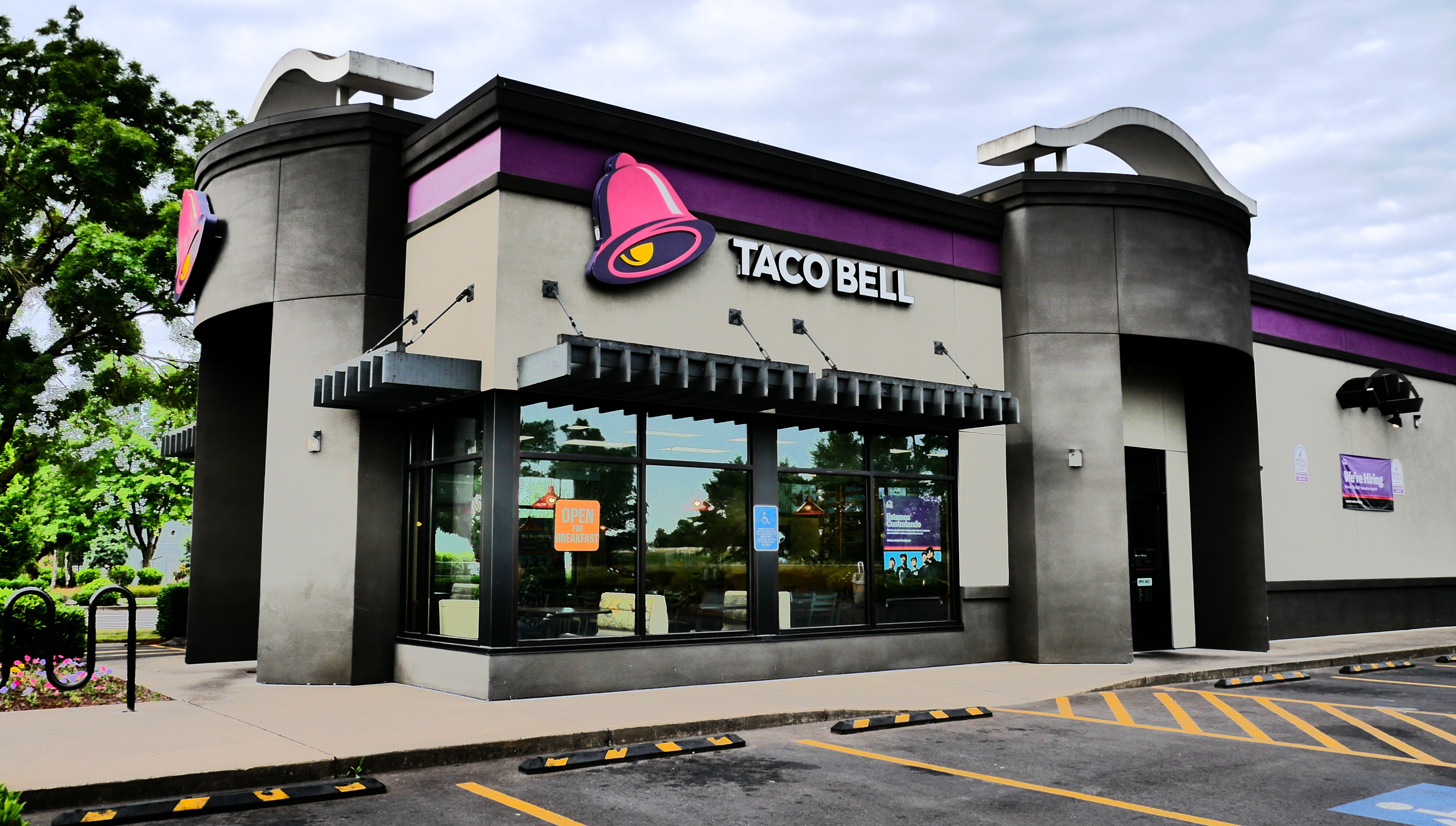 Exterior of a Taco Bell restaurant with purple and gray facade and drive-through lane.