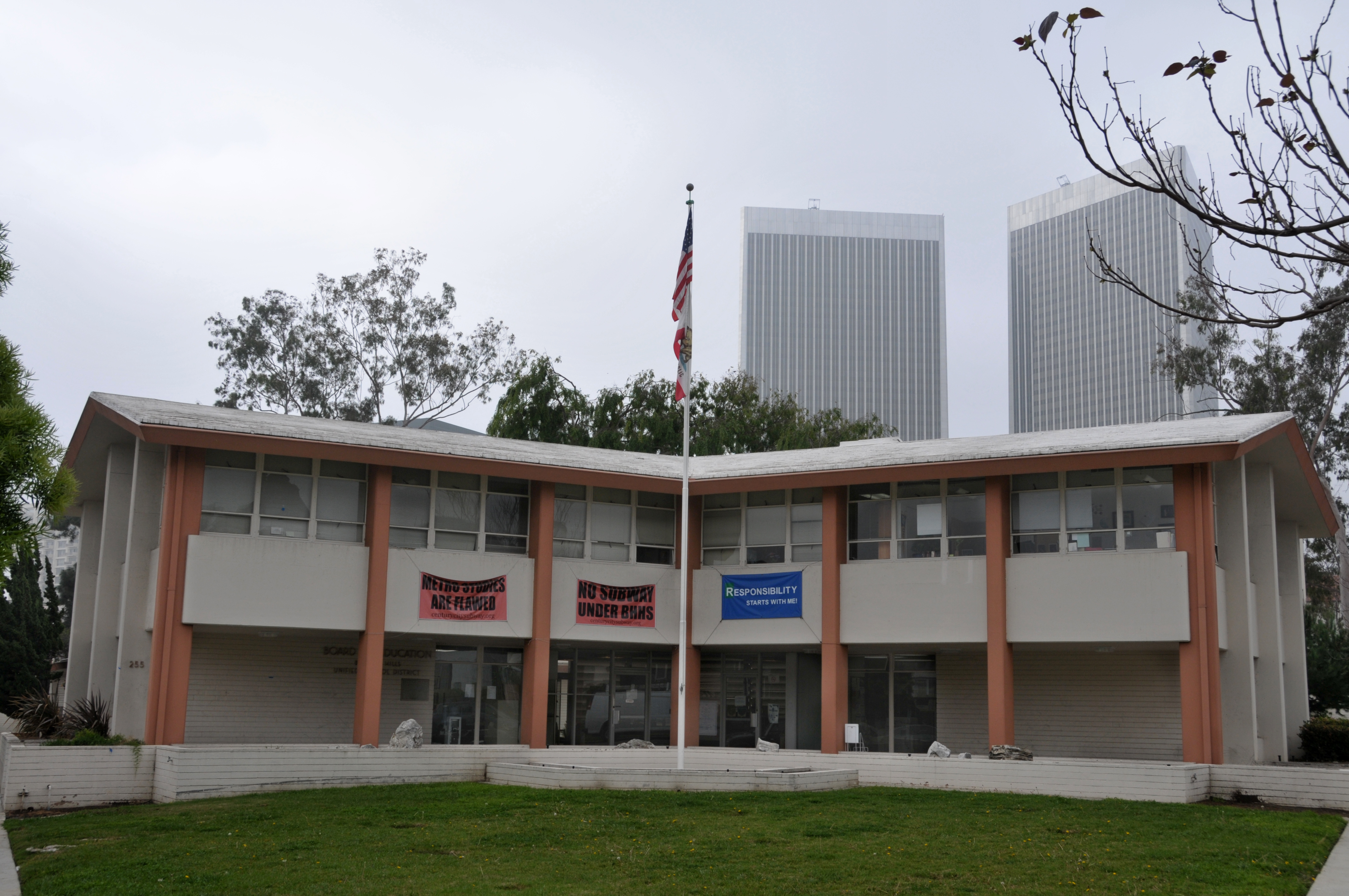 Two-story school district headquarters building with a flagpole and American flag out front.