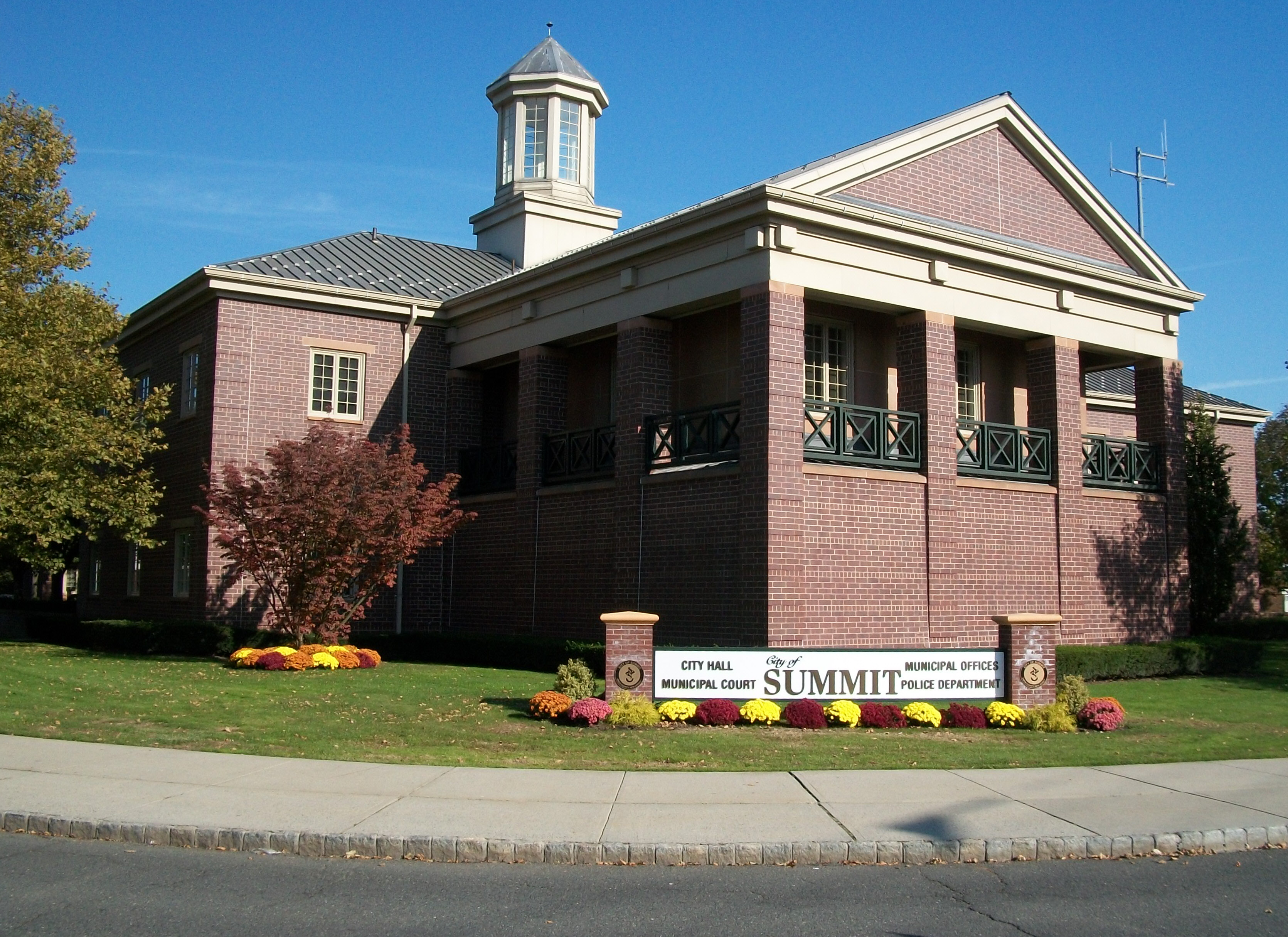 Brick municipal building with columned portico, cupola, and a sign identifying it as Summit City Hall.