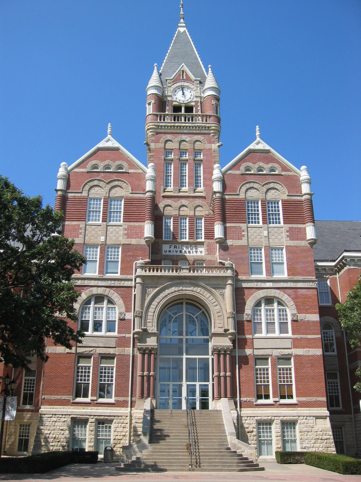 Red-brick Victorian university building with a clock tower and arched entrance.