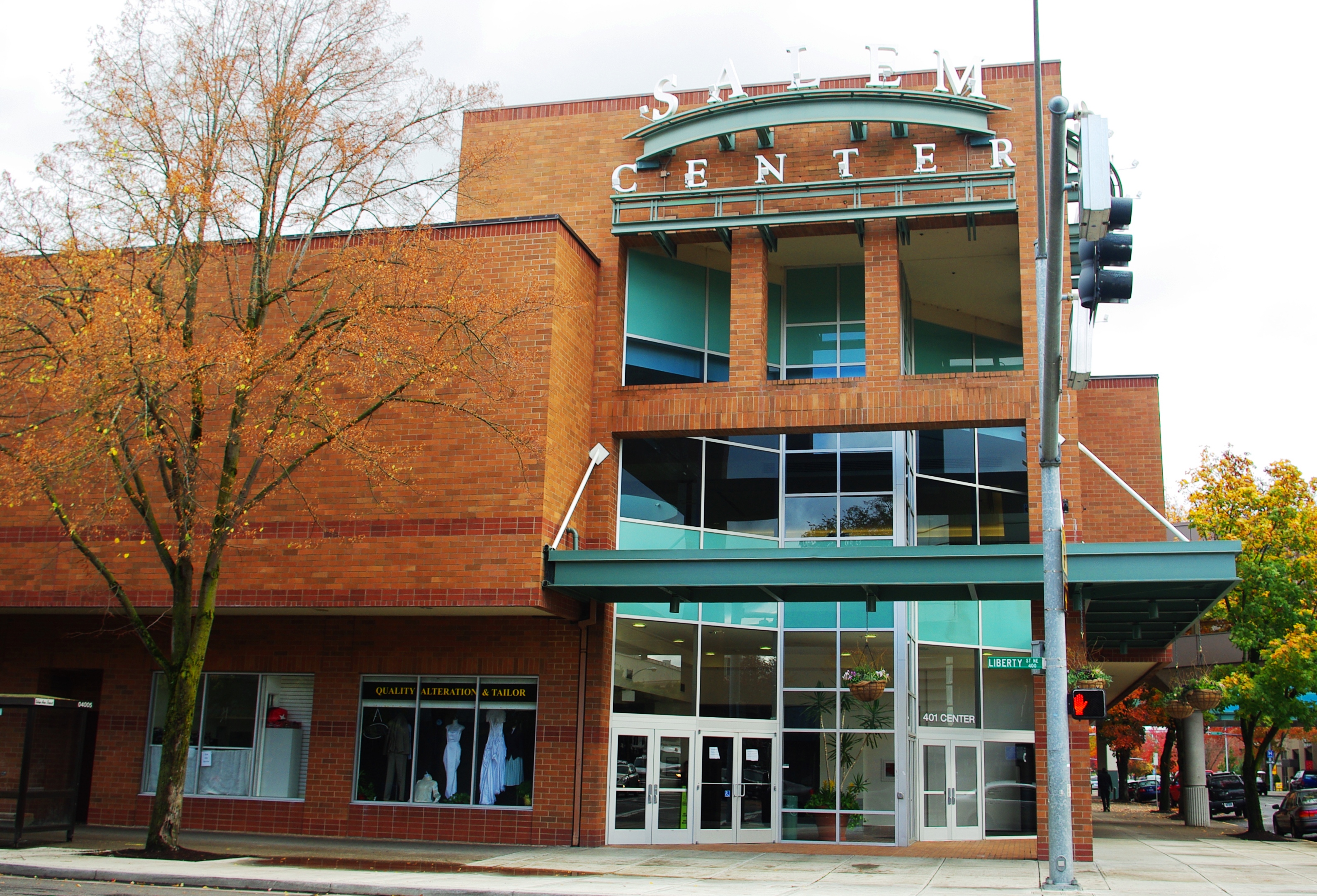 Two-story brick mall exterior with teal accents and large 'CENTER' sign, flanked by trees.
