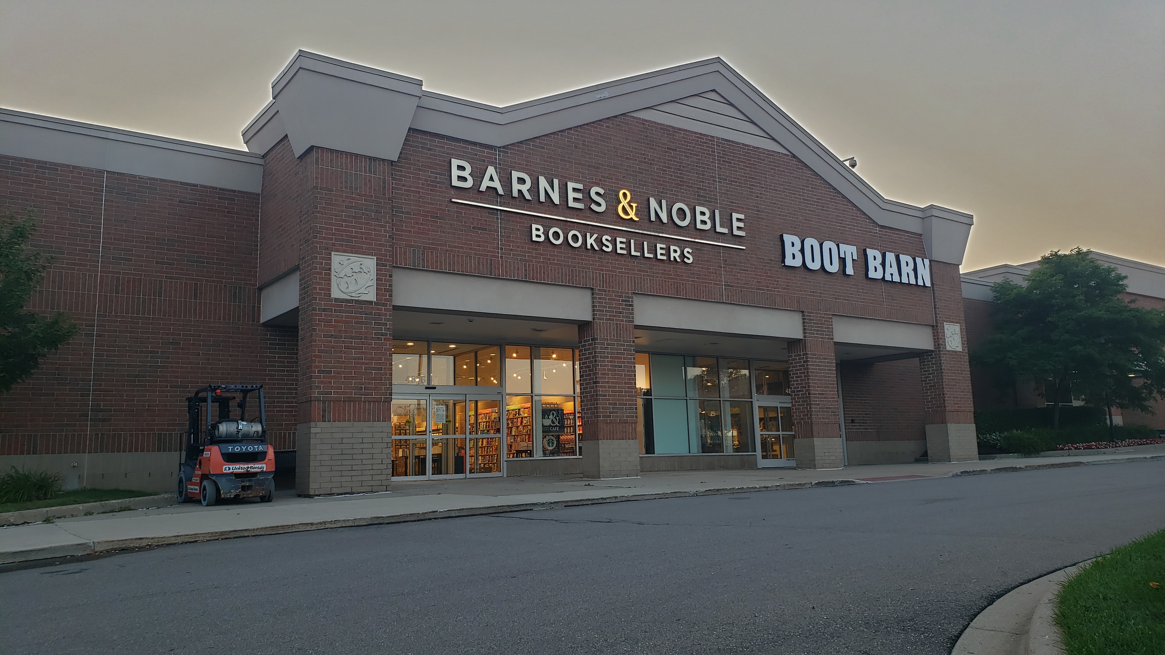 Barnes & Noble storefront at dusk with illuminated signage and brick facade in a strip shopping center.