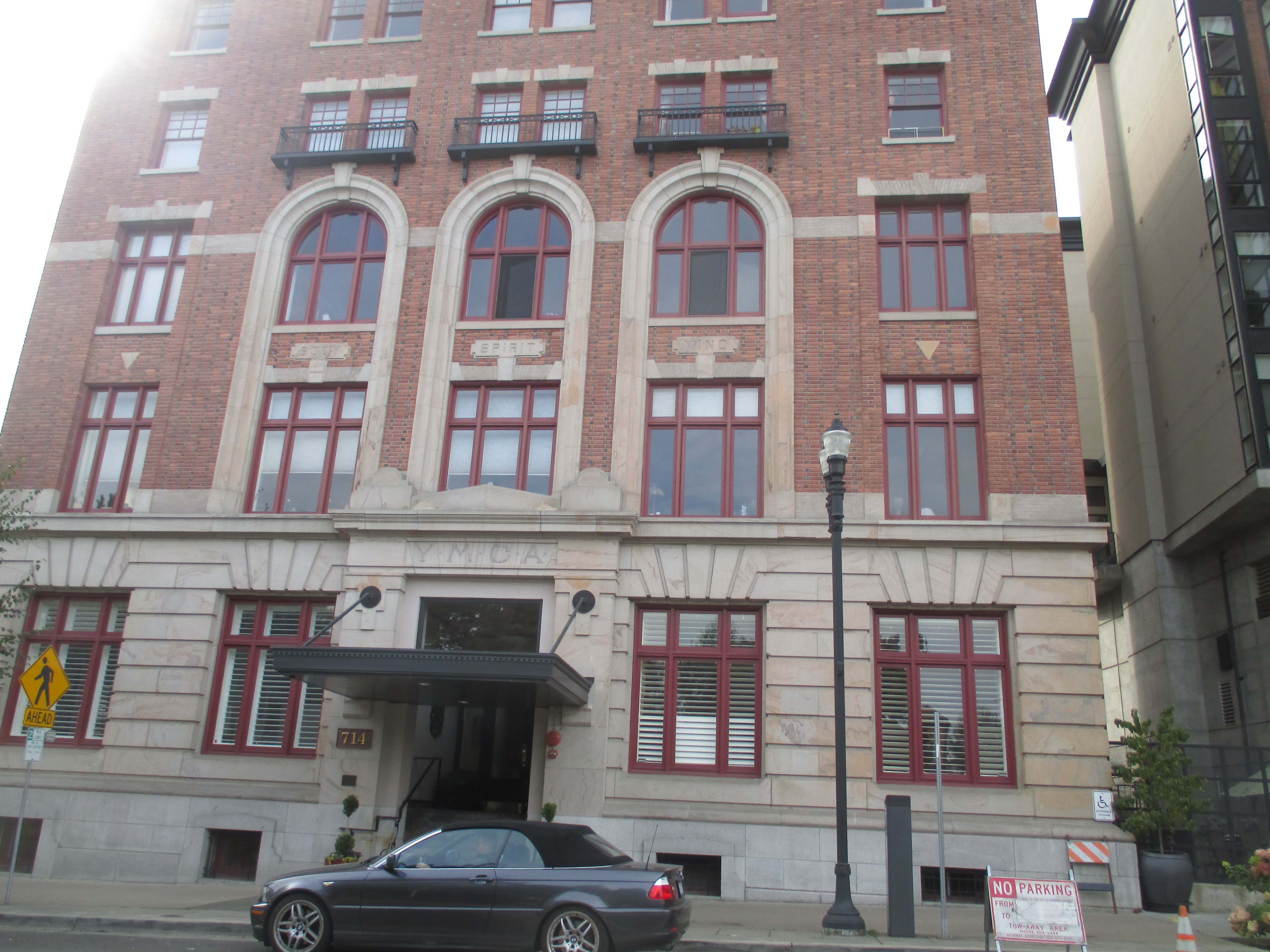 Exterior of a multi-story red brick YMCA building with arched windows.