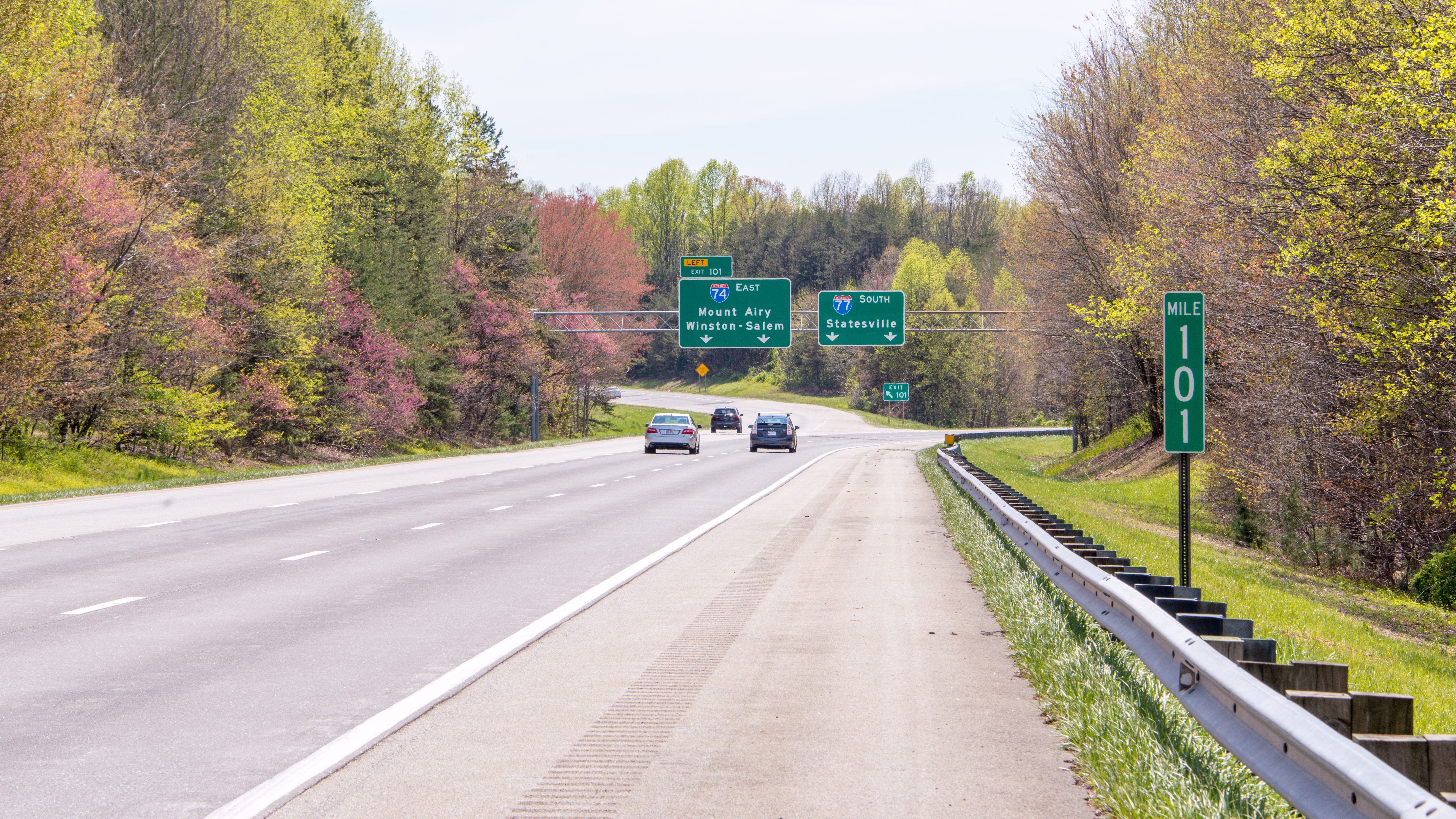 Multi-lane interstate highway with green overhead directional signs and light traffic.