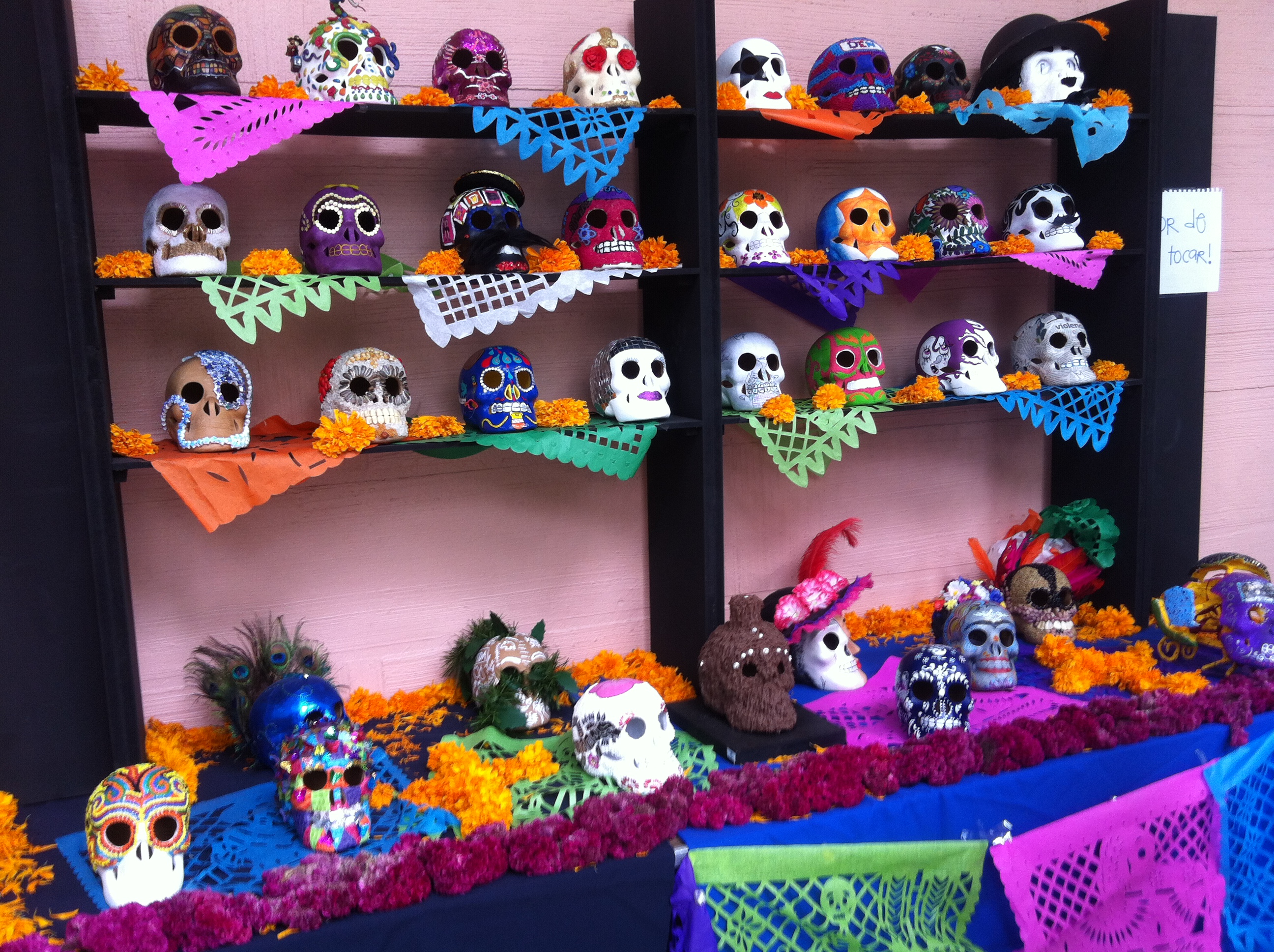 Shelves lined with dozens of brightly decorated sugar skulls and marigold flowers.