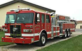 Large red fire department aerial ladder truck parked outside a building.