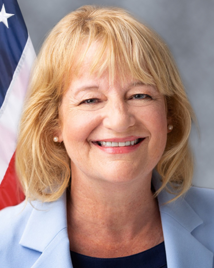 Official portrait of a woman in professional attire against a neutral background.