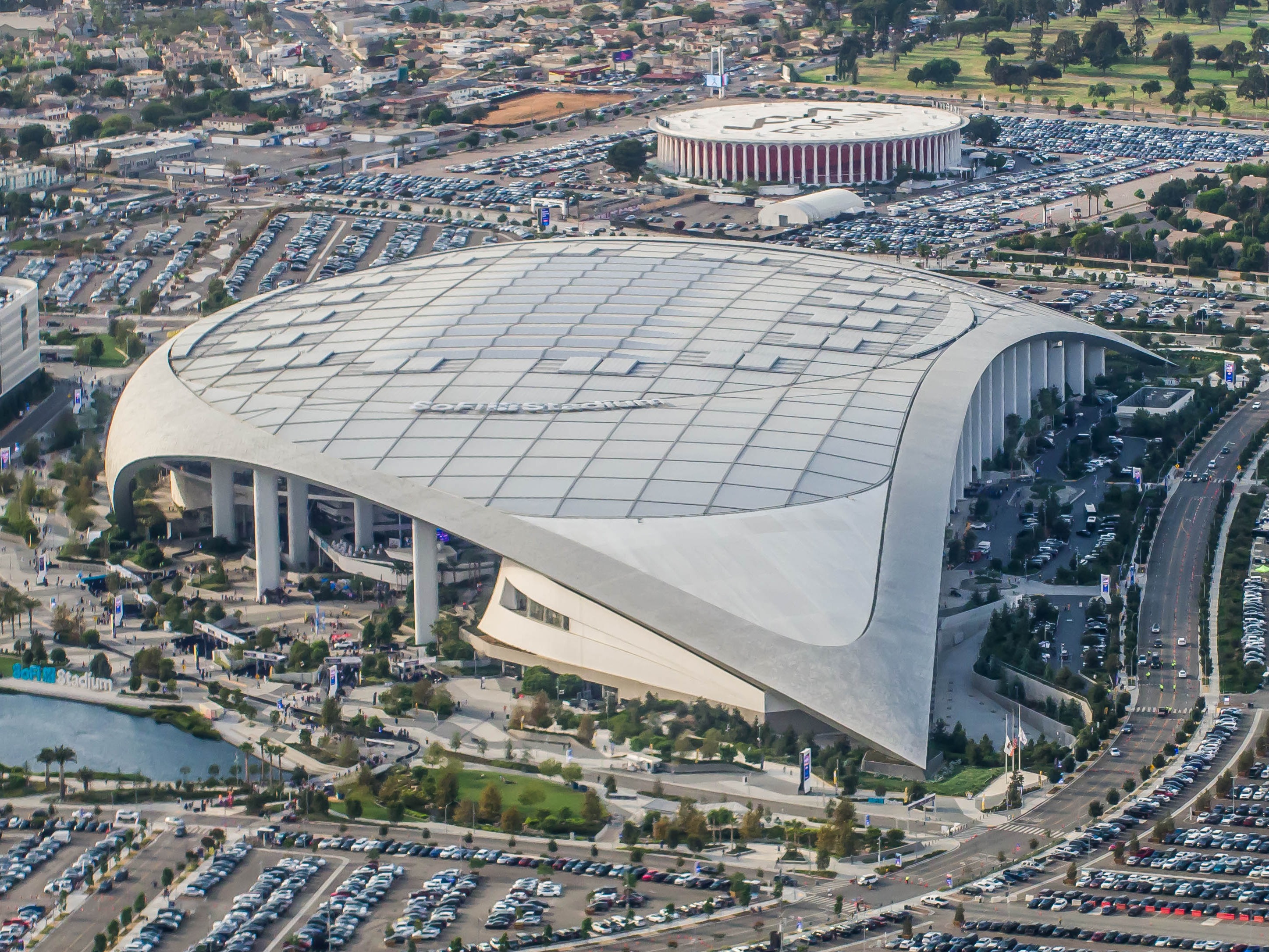 Aerial view of a large domed stadium surrounded by parking lots and a circular arena.