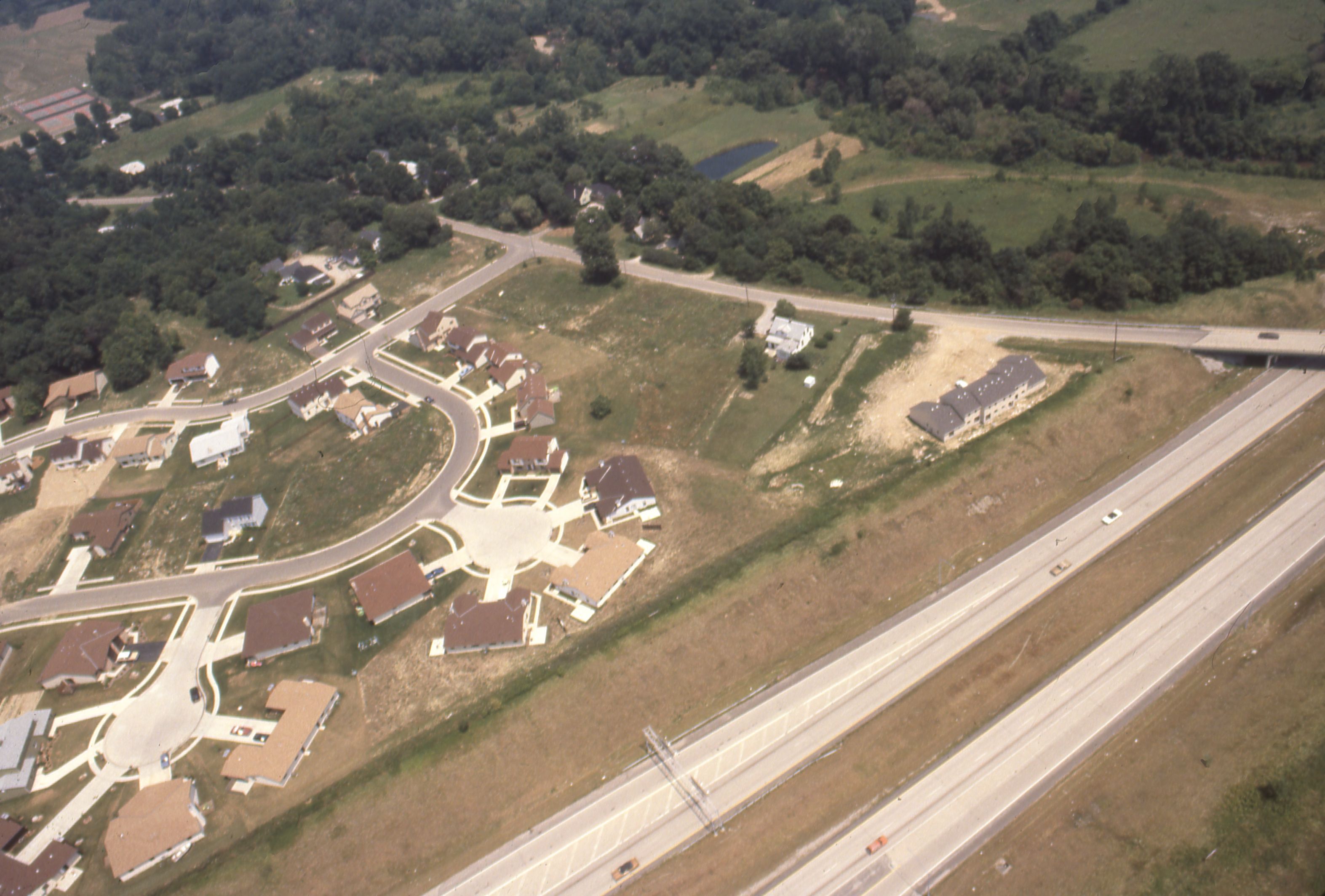 Aerial view of a suburban subdivision under construction with curved streets and cleared lots.