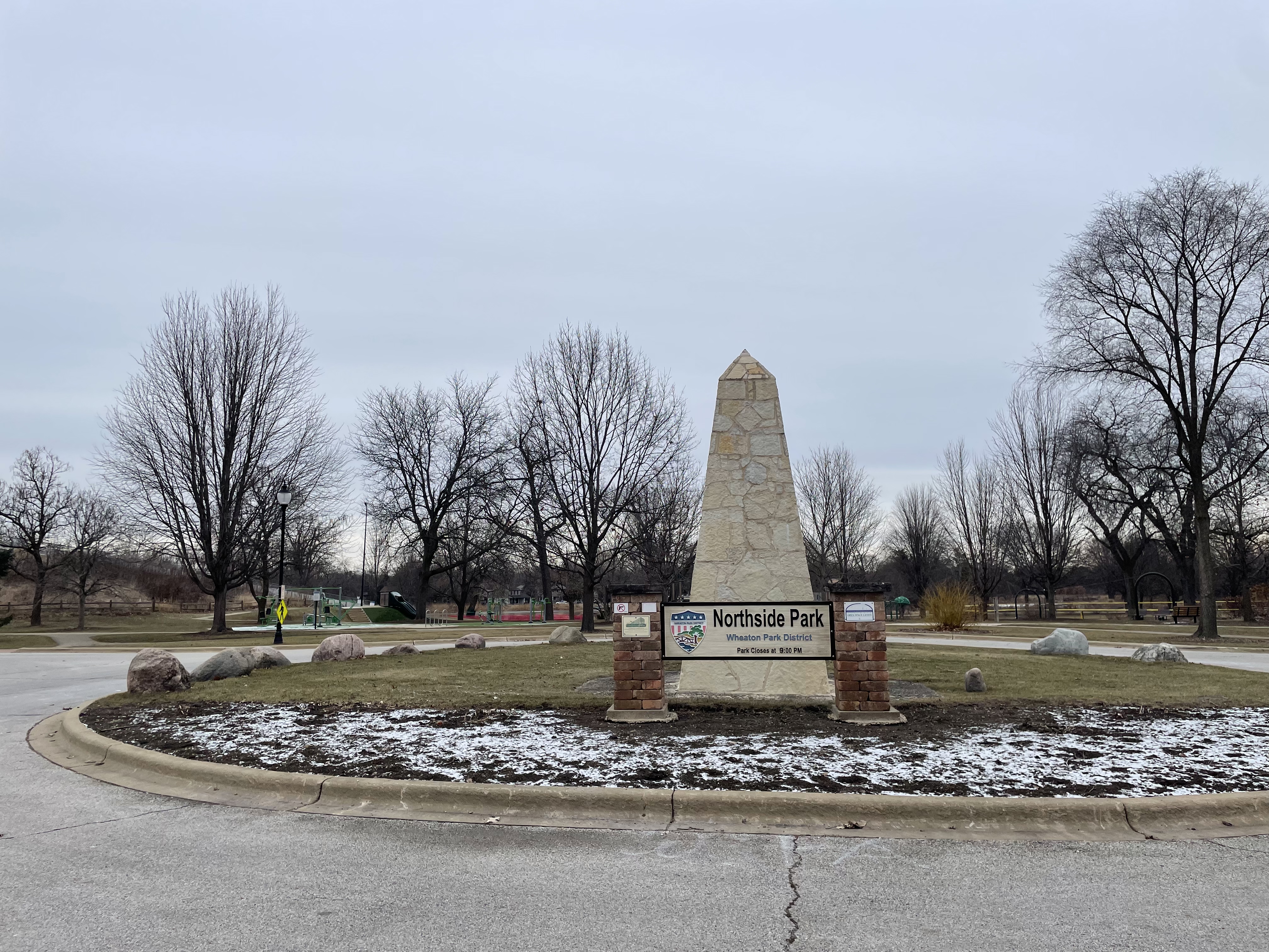 A park entrance sign reading Northside Park surrounded by winter landscaping.