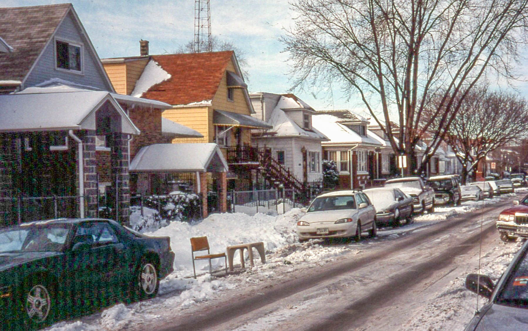 Two chairs placed in a snow-covered street to reserve a parking spot.