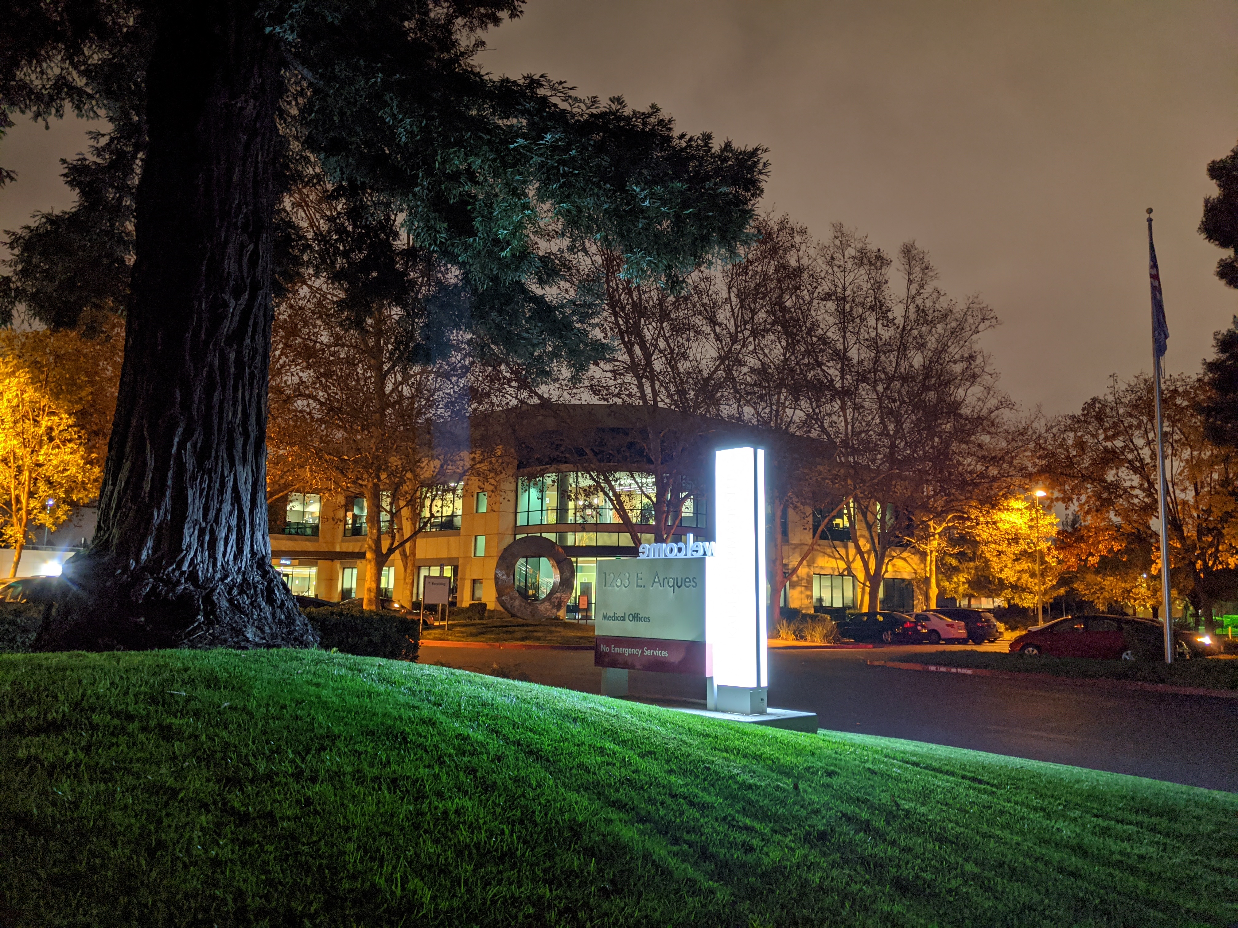 Illuminated Kaiser Permanente sign outside a medical building at night.