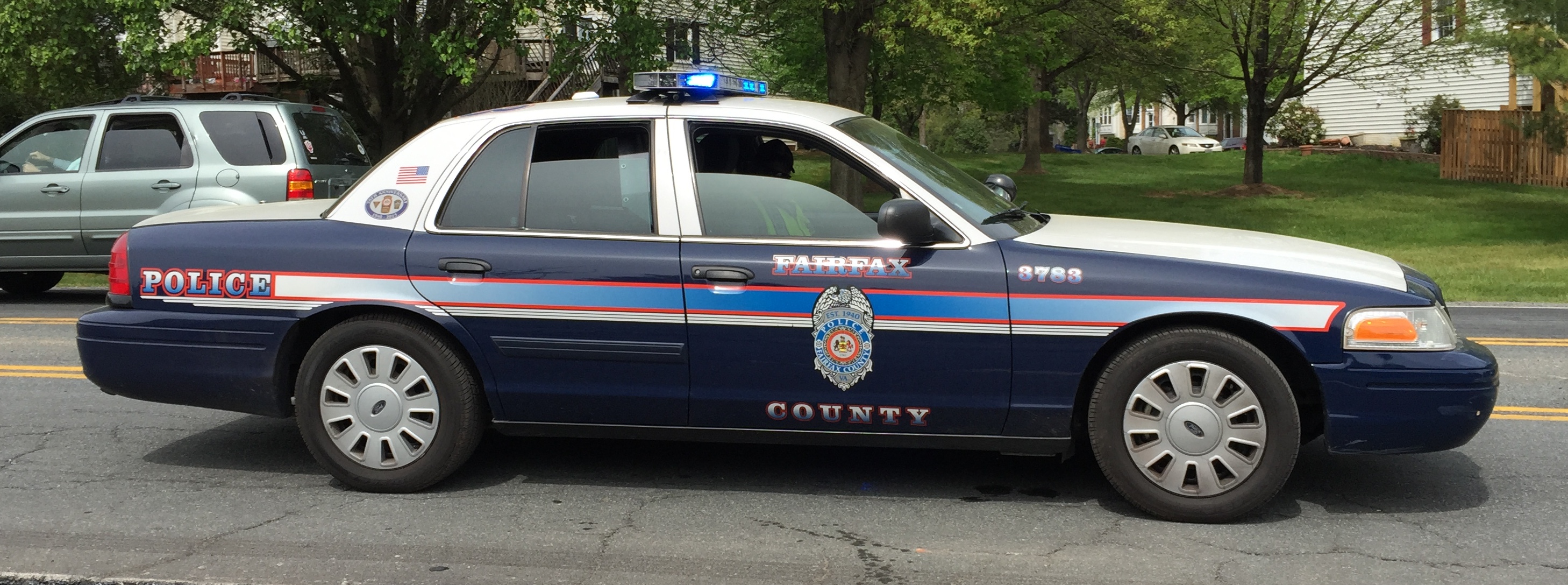 A blue-and-white Fairfax County Police cruiser parked on a road.