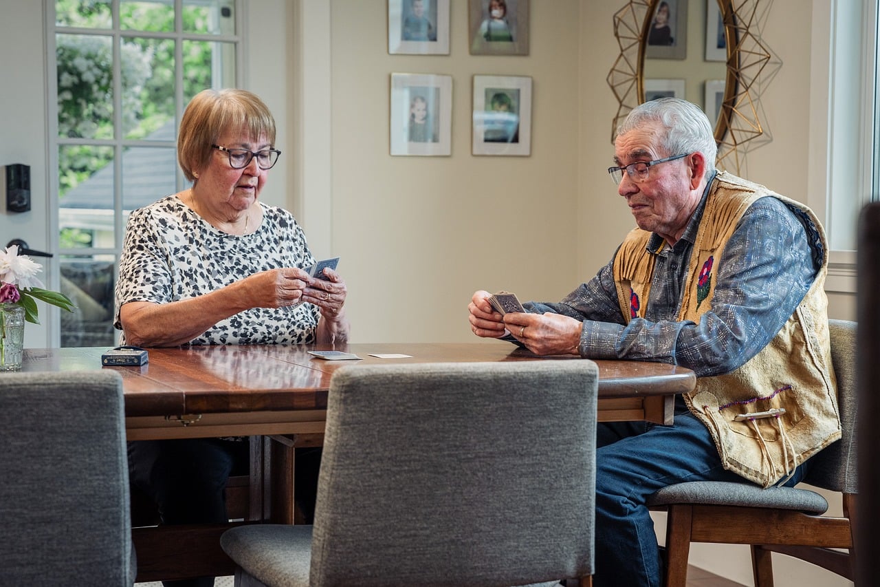 Card game, elderly couple, indoors, table, house, living room, chair, game, grandmother, grandfather, vehicle, entertain