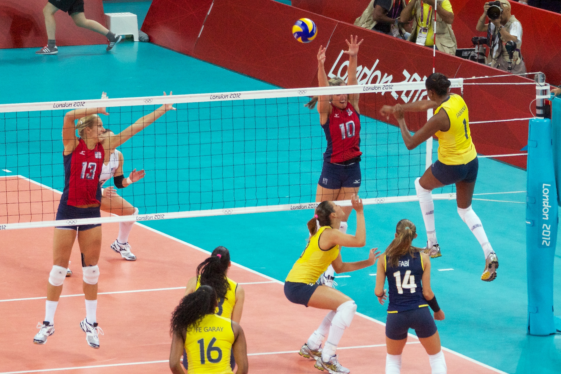 An indoor volleyball match in progress at a large arena during the Olympics.