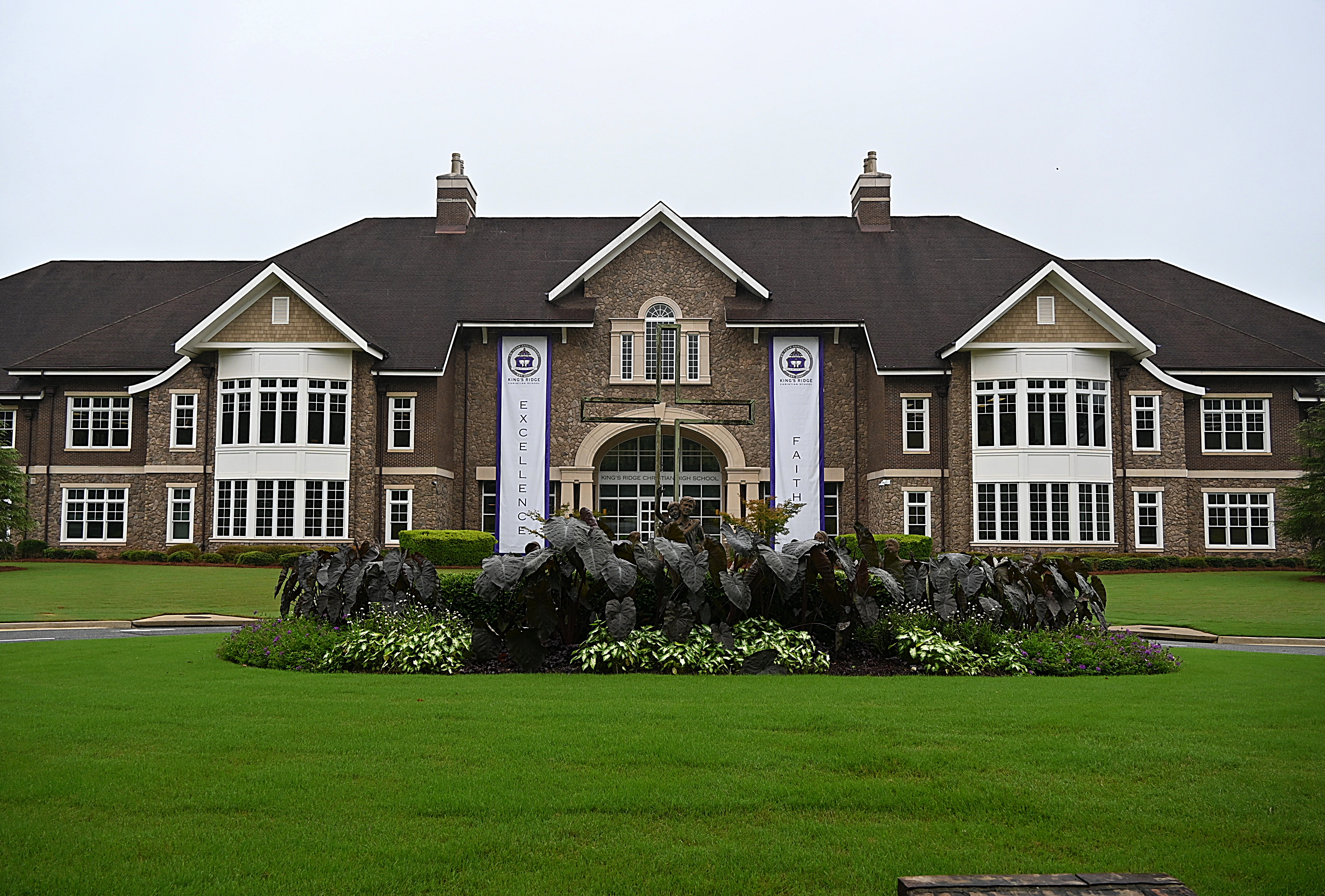 Two-story brick private school building with arched entrance and circular garden.