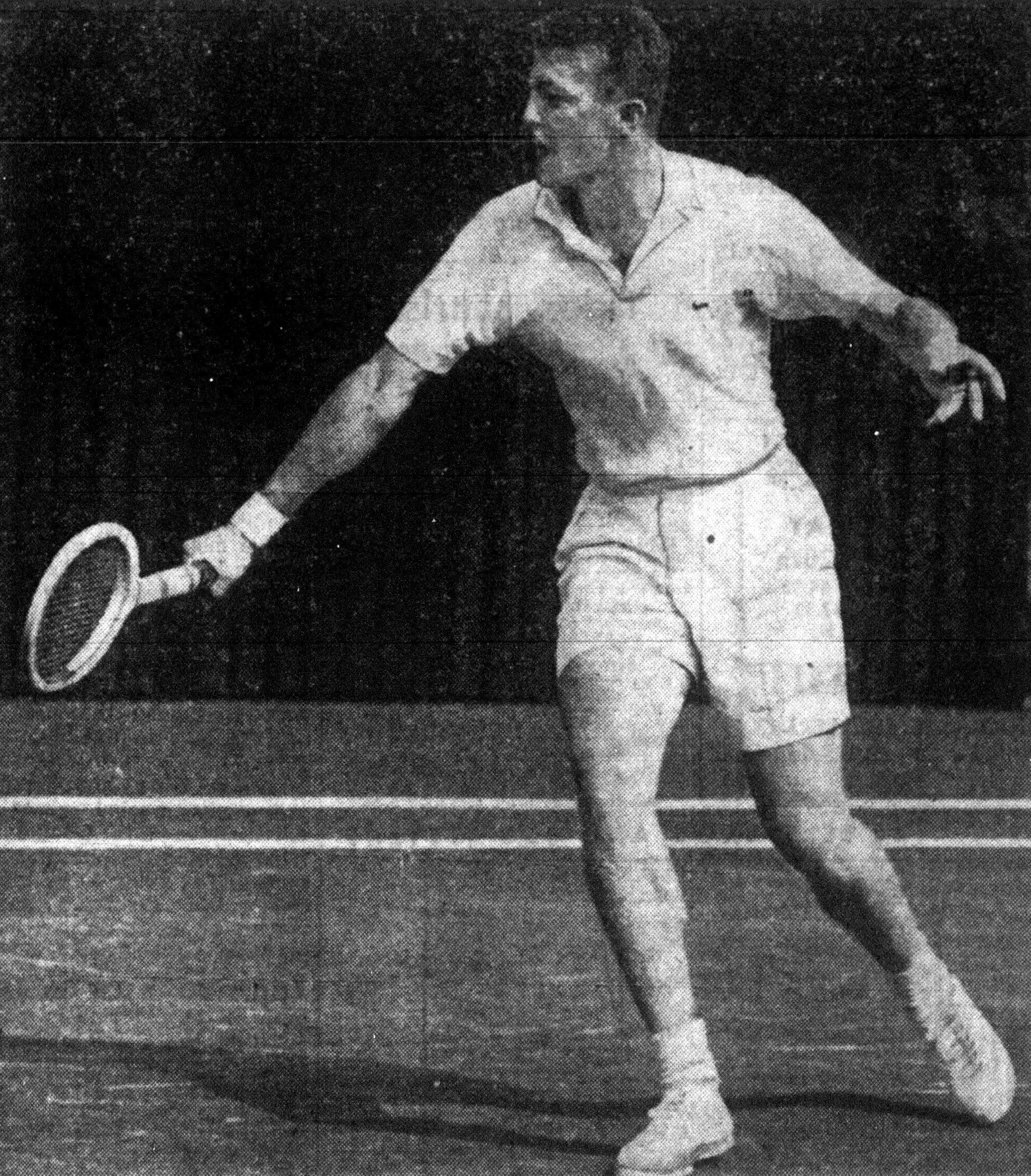 Male tennis player in white shorts and shirt swinging a wooden racquet on a court.