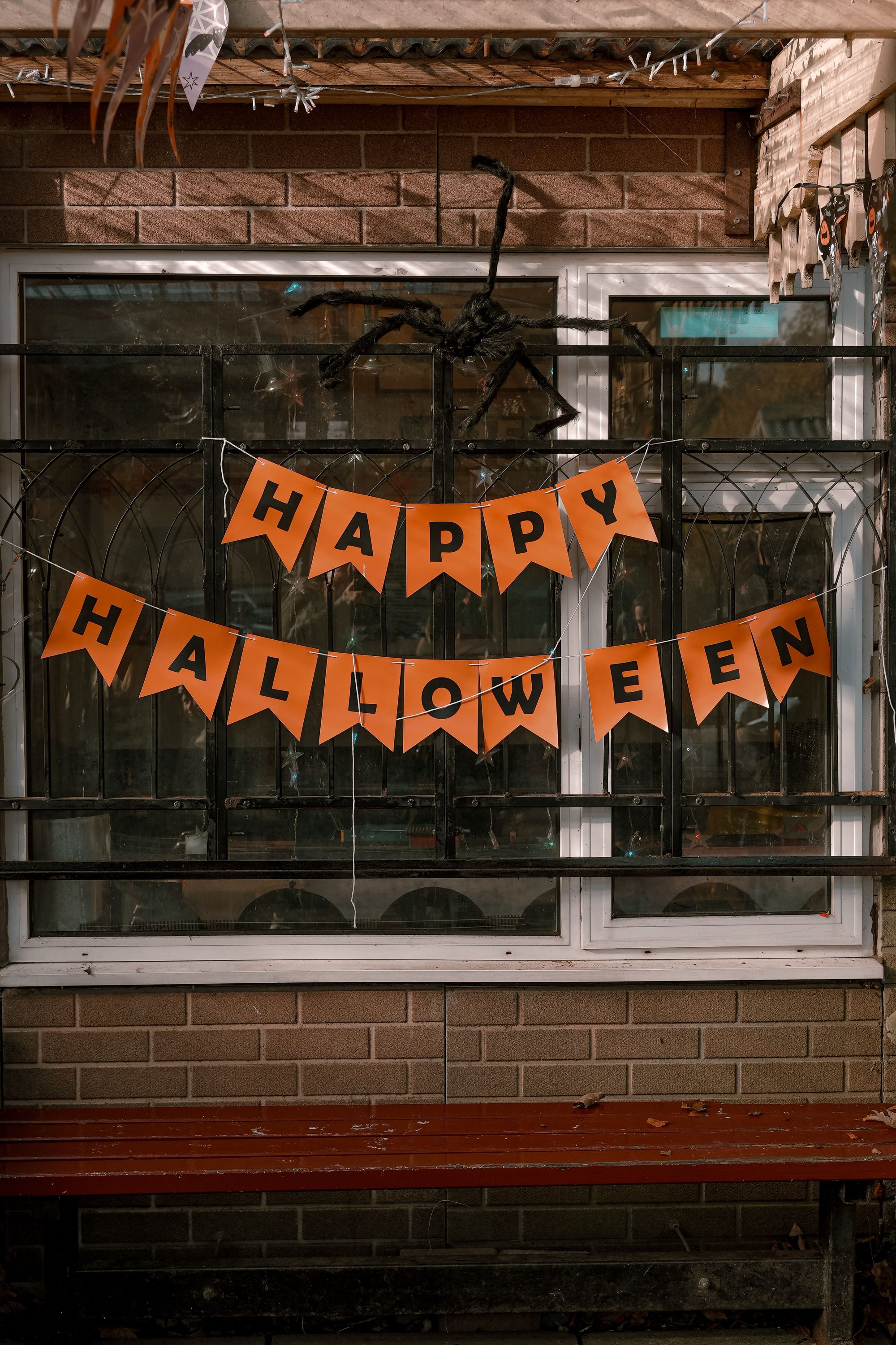 Festive Halloween display with orange bunting and spider decor on a brick wall.