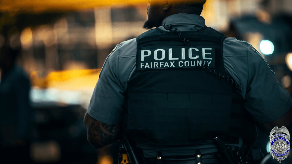 Fairfax County Police officer seen from behind wearing a black tactical vest.