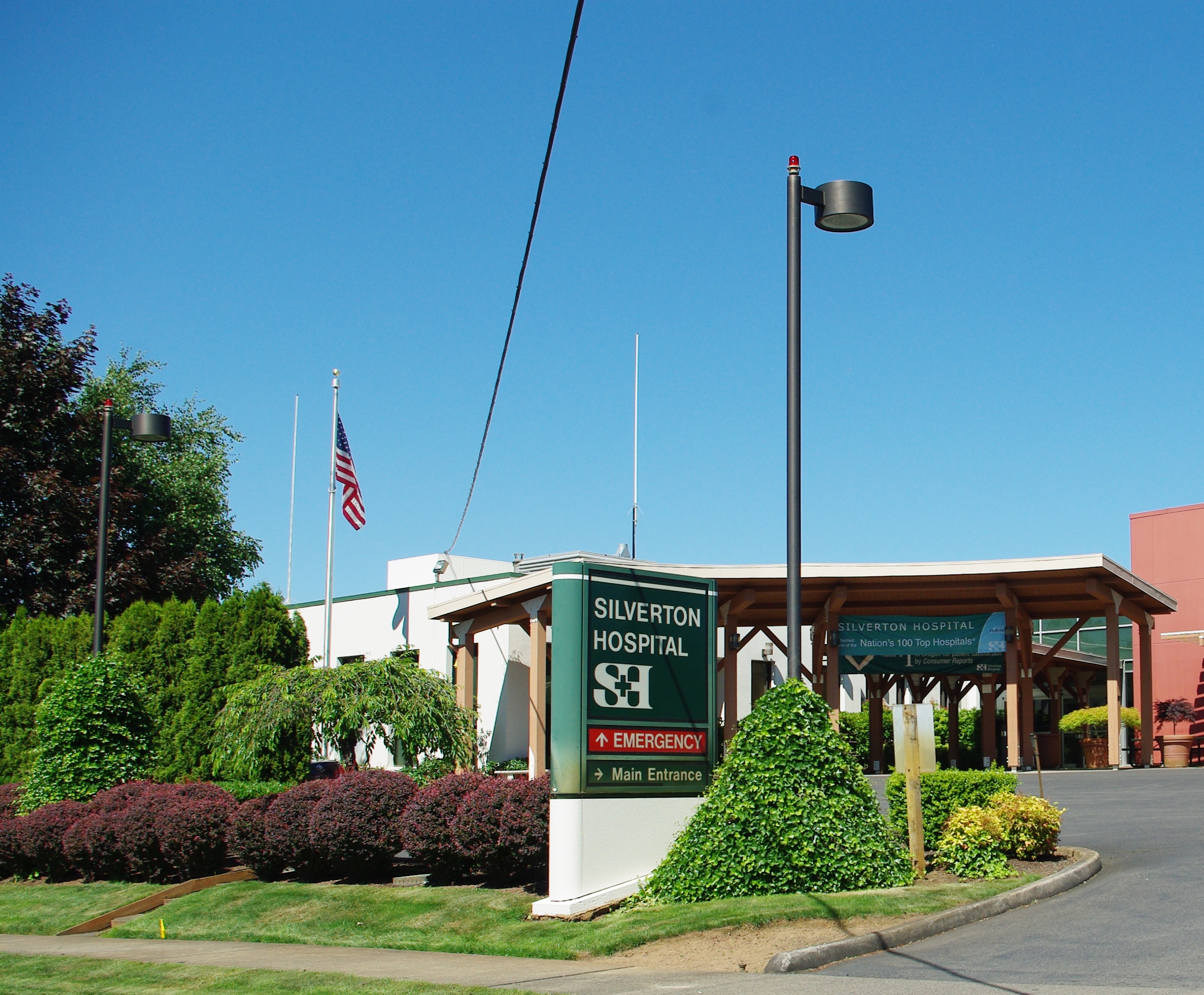 Hospital entrance sign and covered canopy with an American flag on a flagpole.
