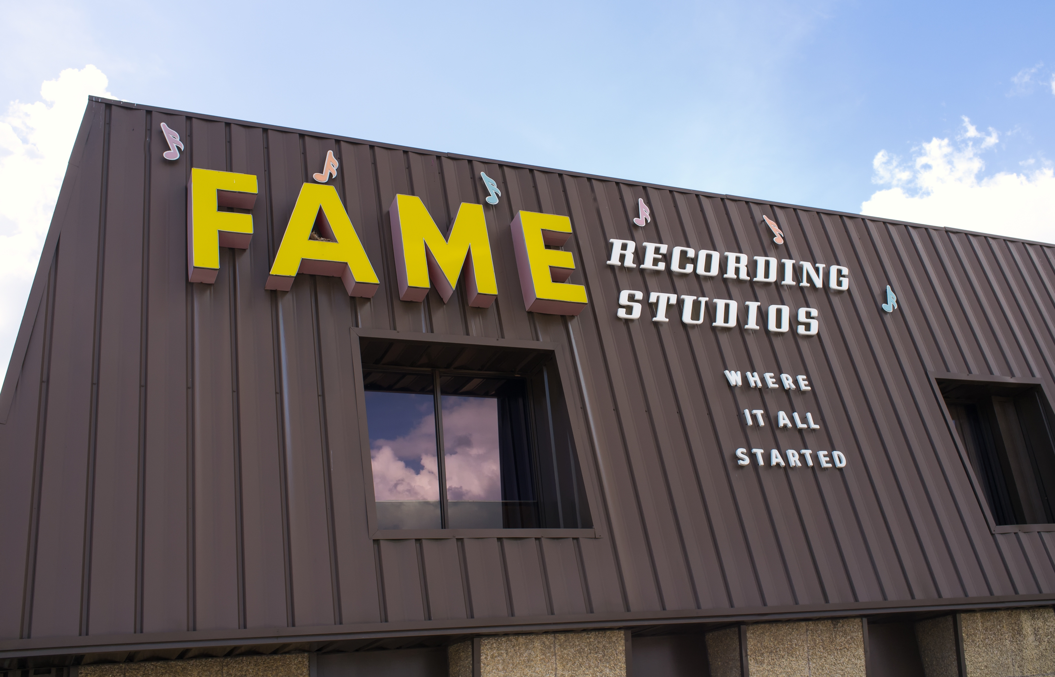 Exterior of a brown metal building with large yellow letters reading FAME Recording Studios.