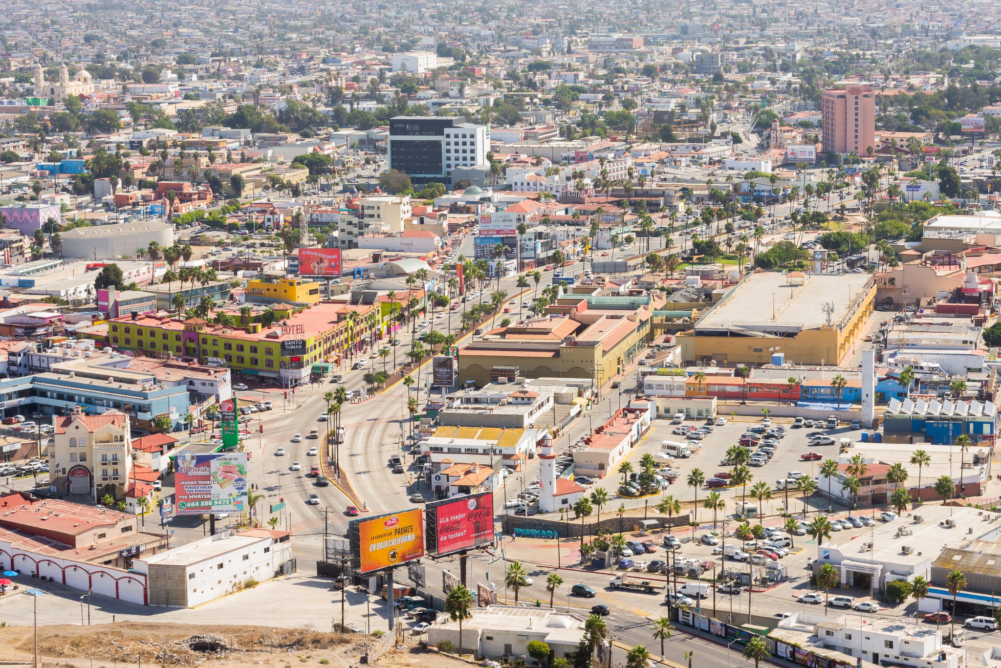 Aerial view of a dense urban downtown with colorful buildings and palm-lined streets.