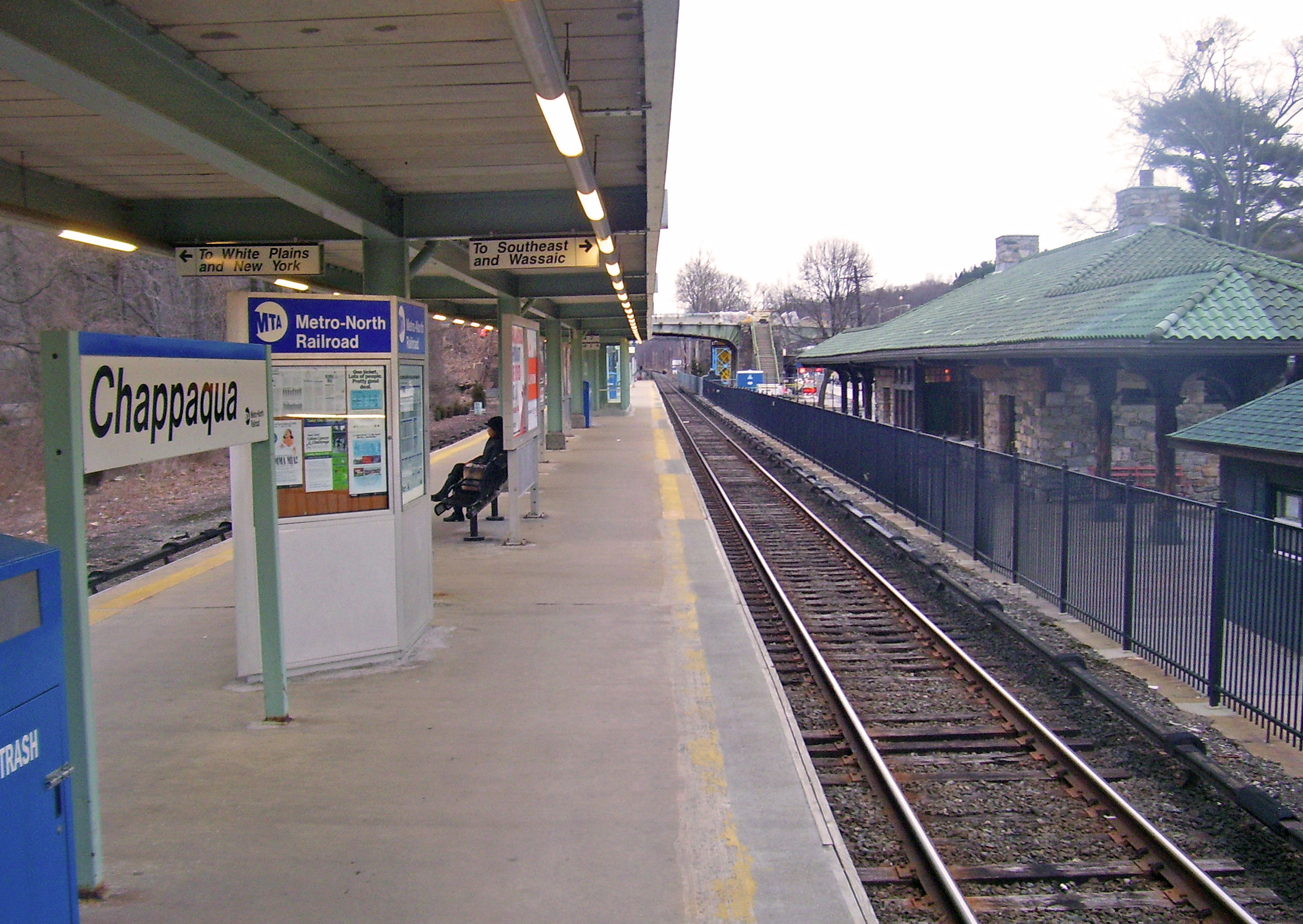 Metro-North Railroad platform at Chappaqua station with benches, signage, and a green-roofed building.