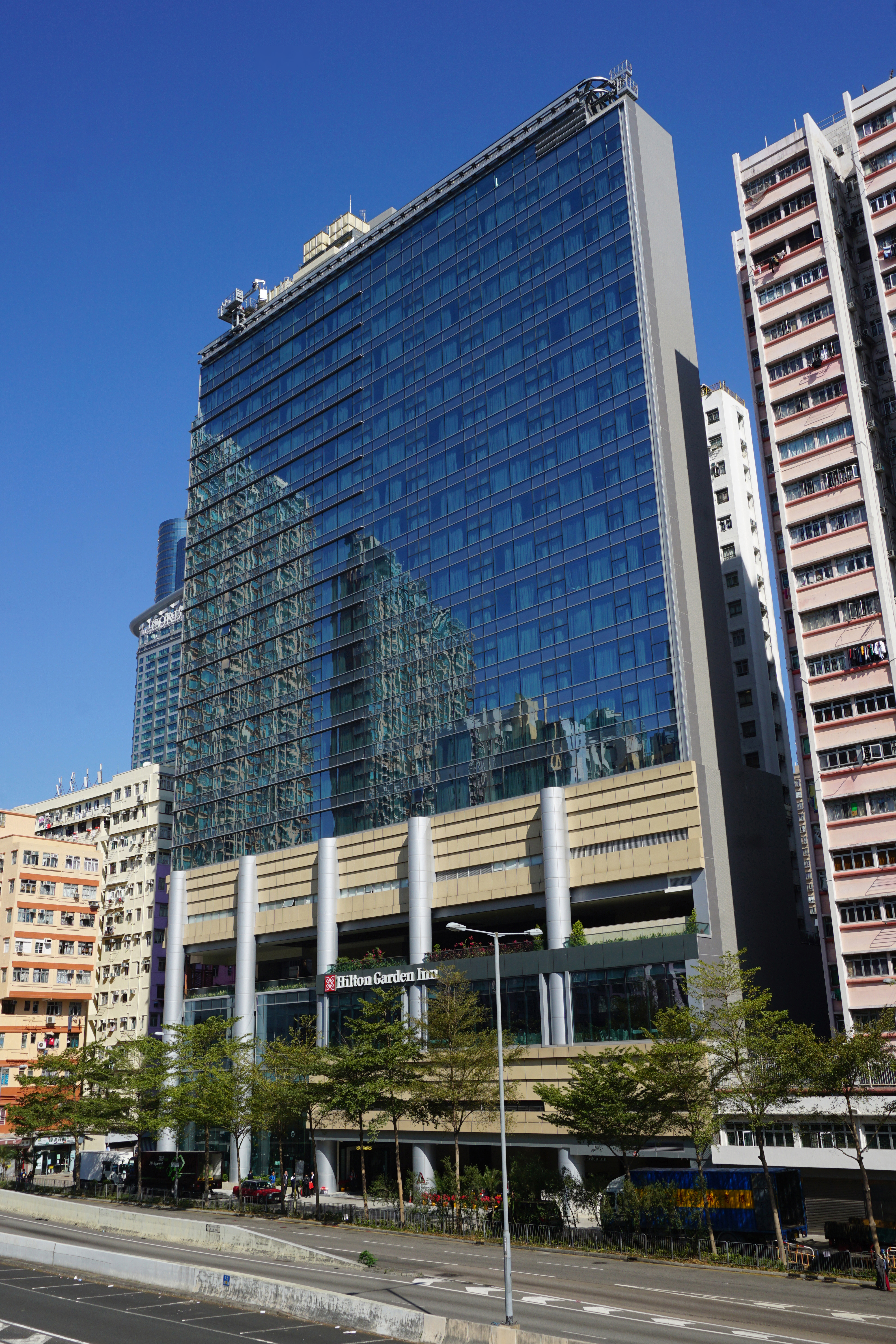 Multi-story glass-curtain-wall hotel tower with Hilton Garden Inn signage at street level.
