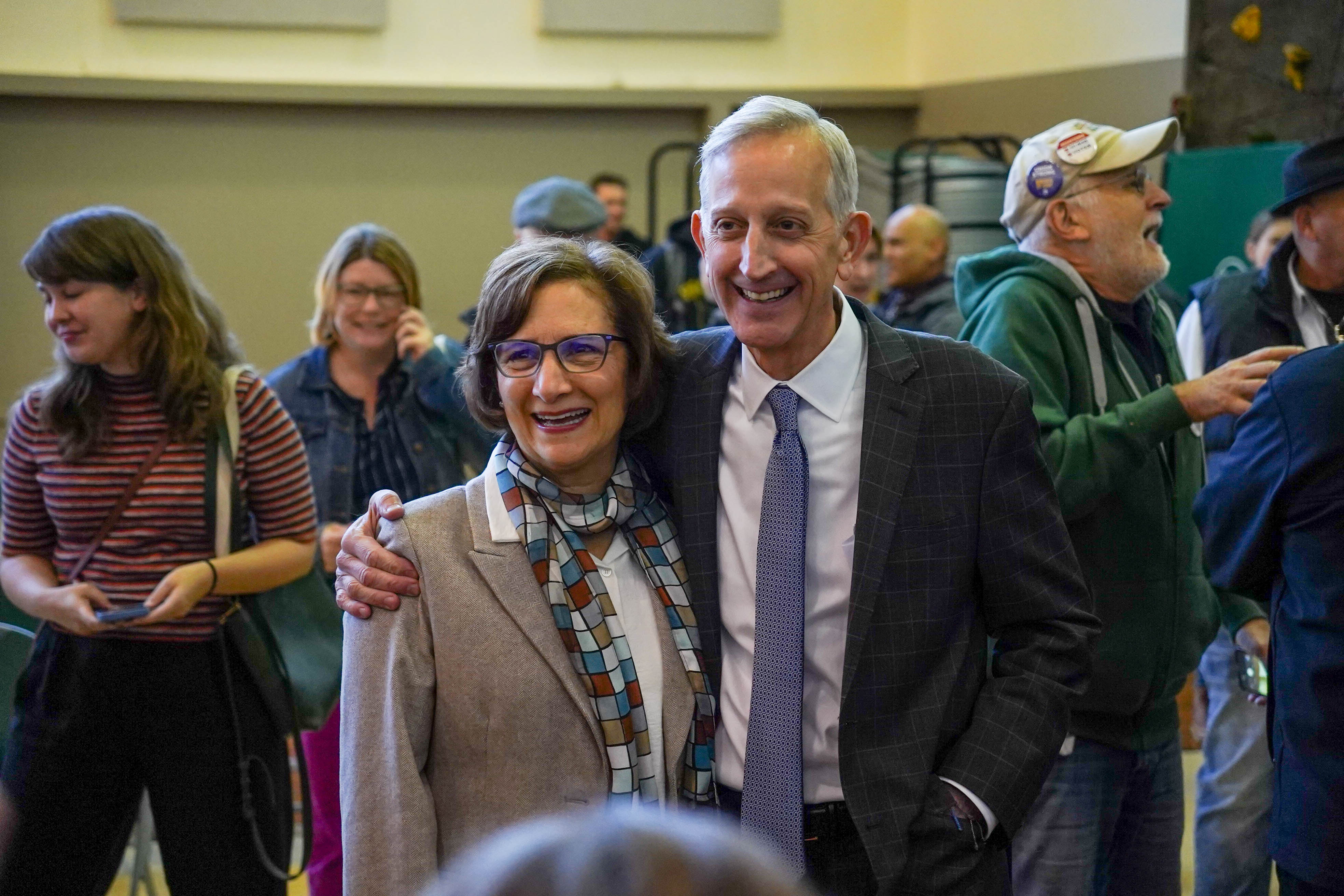 Two people smiling and posing together at an indoor community gathering.