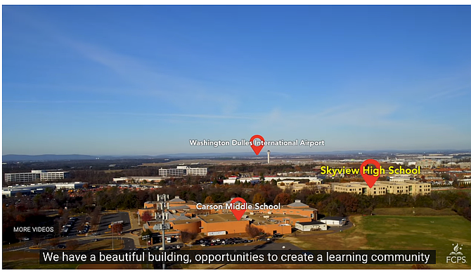 Aerial view of a school campus with green athletic fields and suburban development nearby.