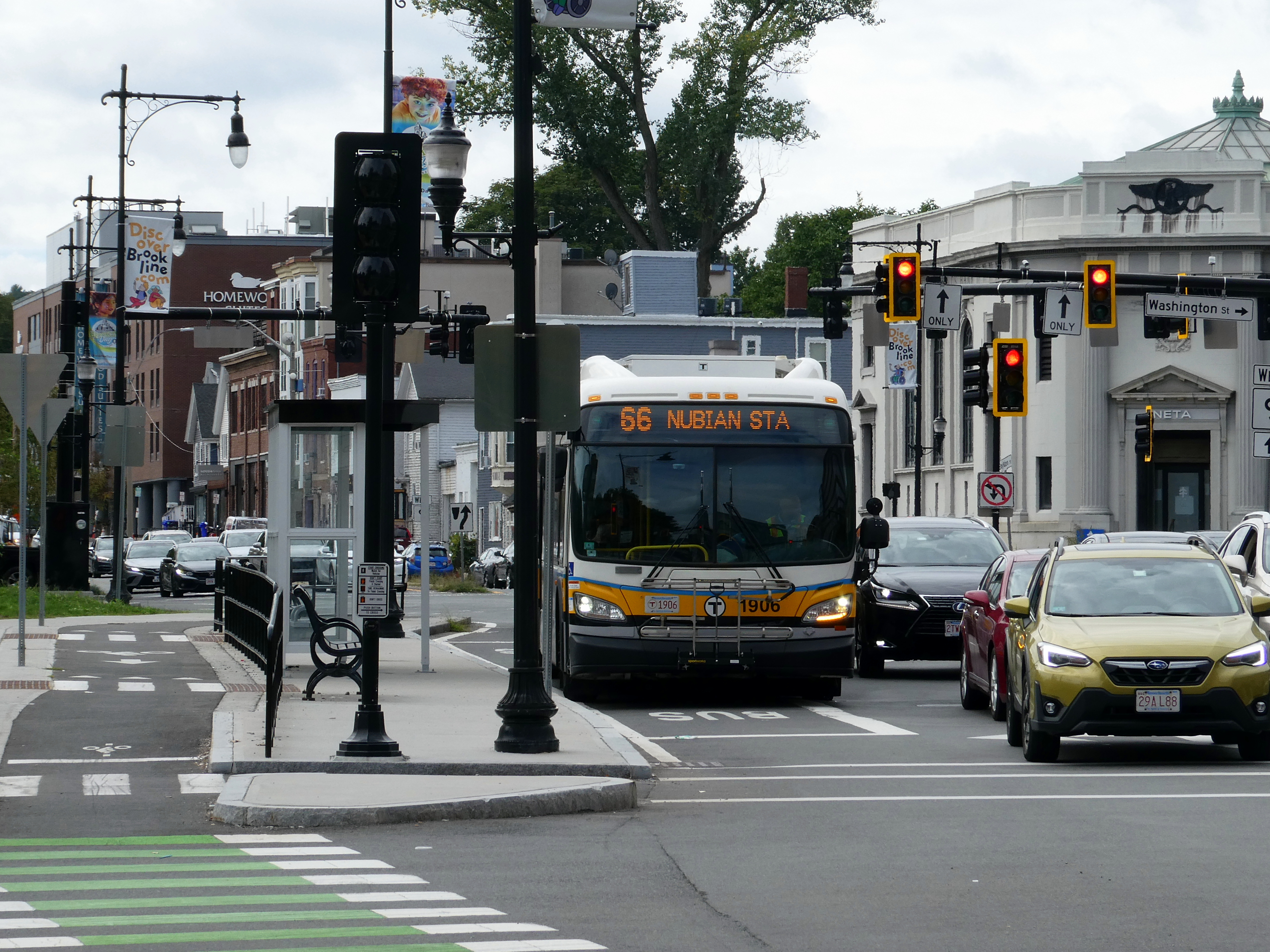 An MBTA Route 66 bus at a busy urban intersection with traffic signals.