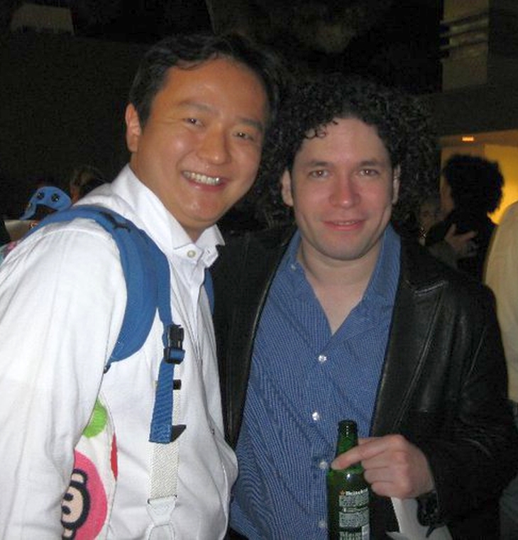 Two men smiling together at an indoor post-performance event, one holding a beer bottle.