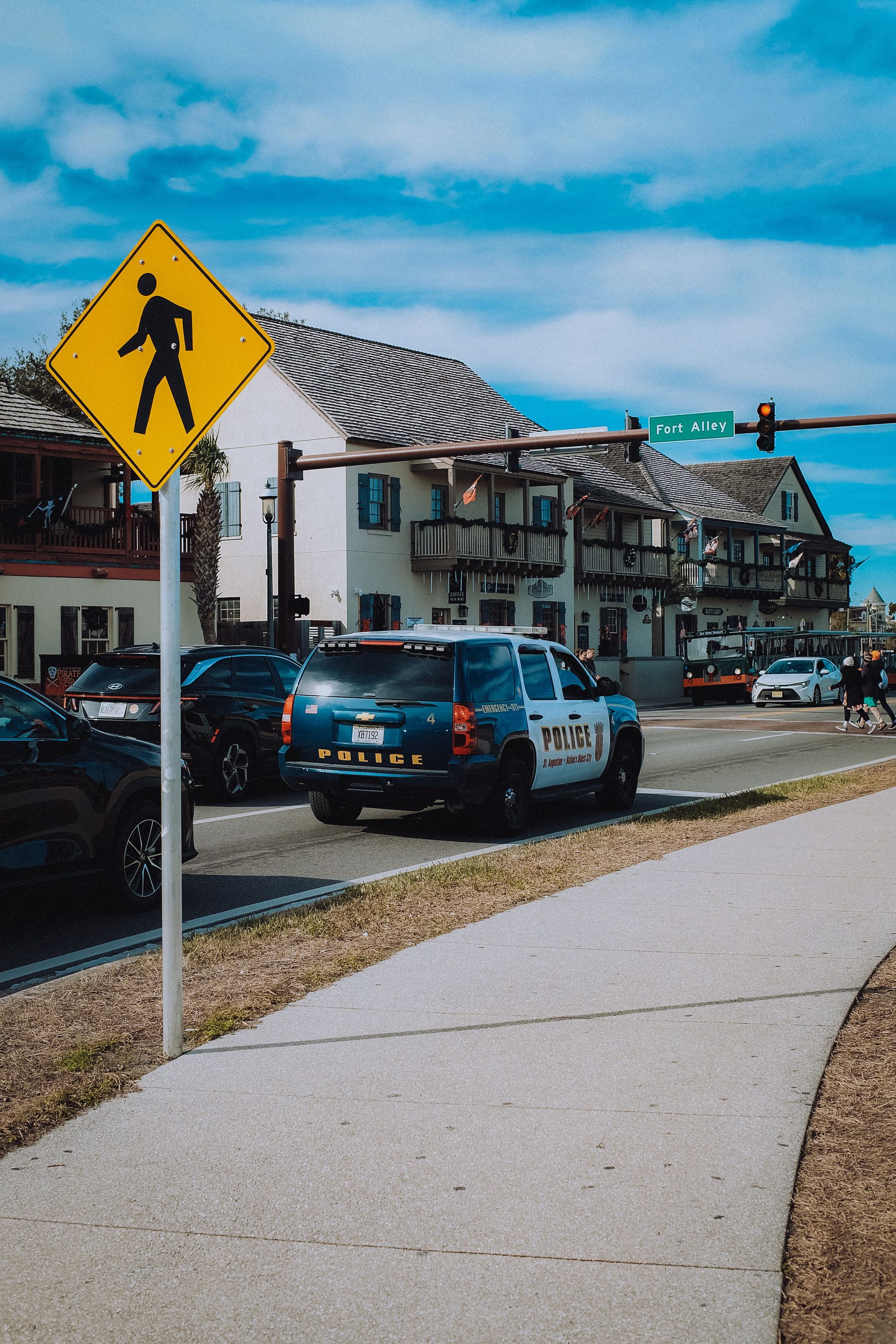 A police cruiser near a pedestrian crossing sign on a sunny day in a small town.