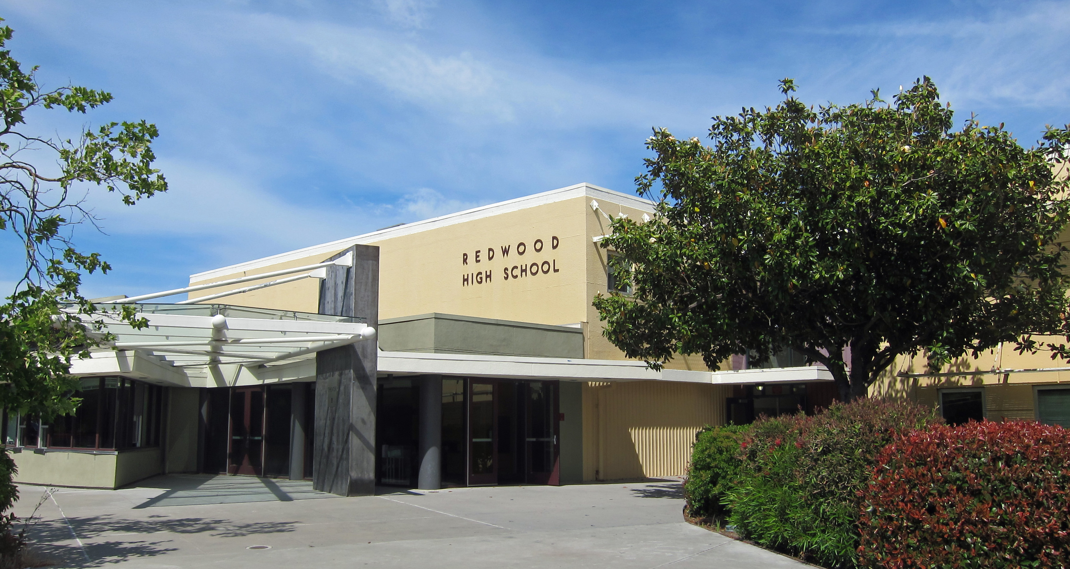 Main entrance of a single-story school building with signage and landscaping.