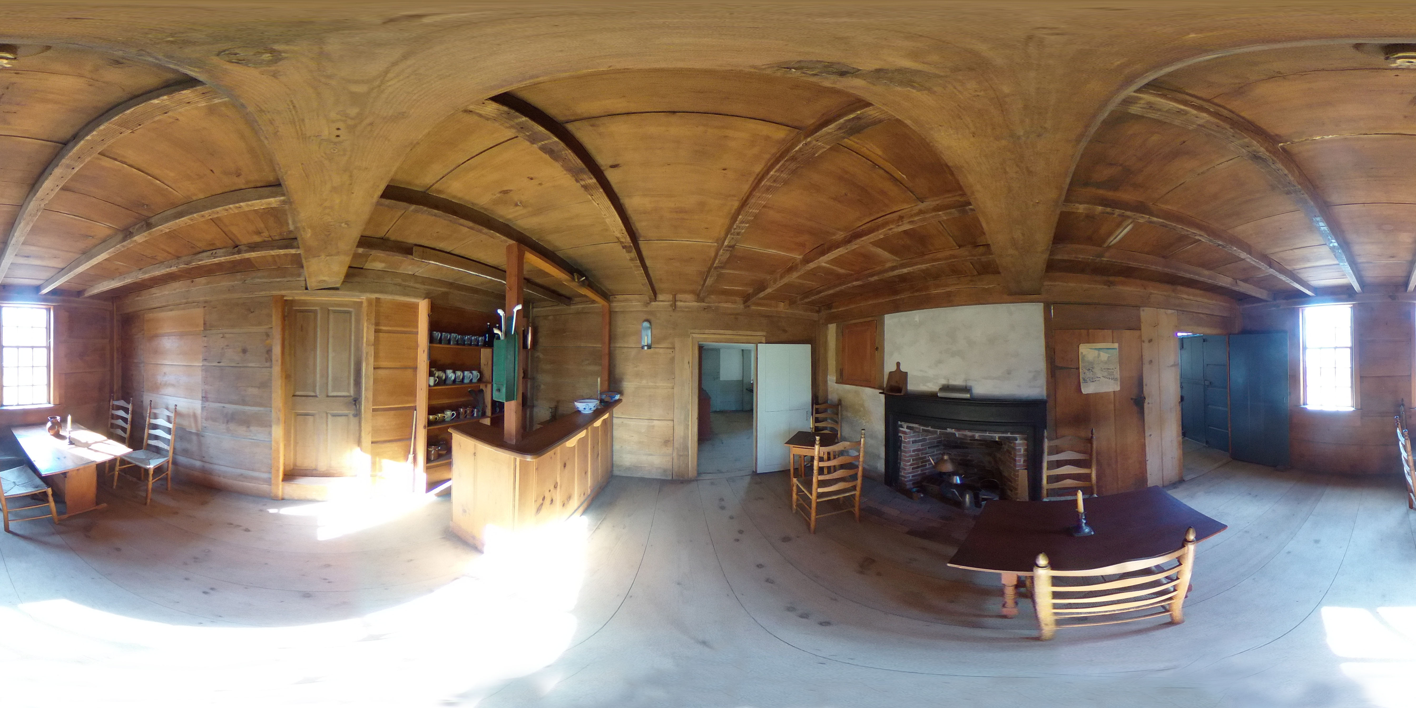 Colonial-era tavern room interior with wooden walls, bar counter, pewter mugs, and a fireplace.