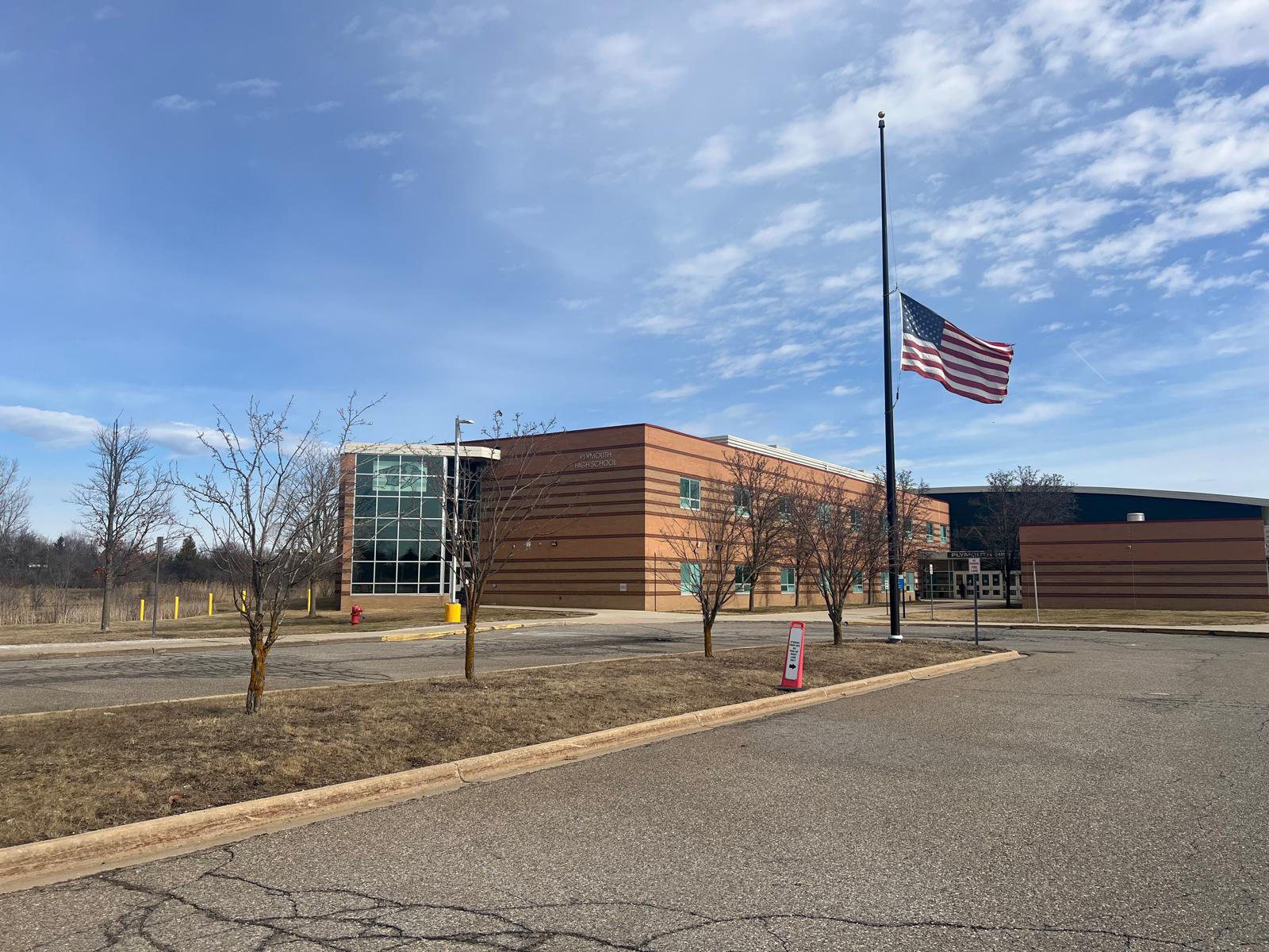 Modern brick school building with brown horizontal cladding and an American flag on a flagpole.