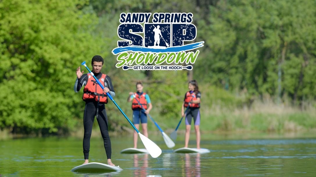 Three stand-up paddleboarders on calm water with event logo overlay.
