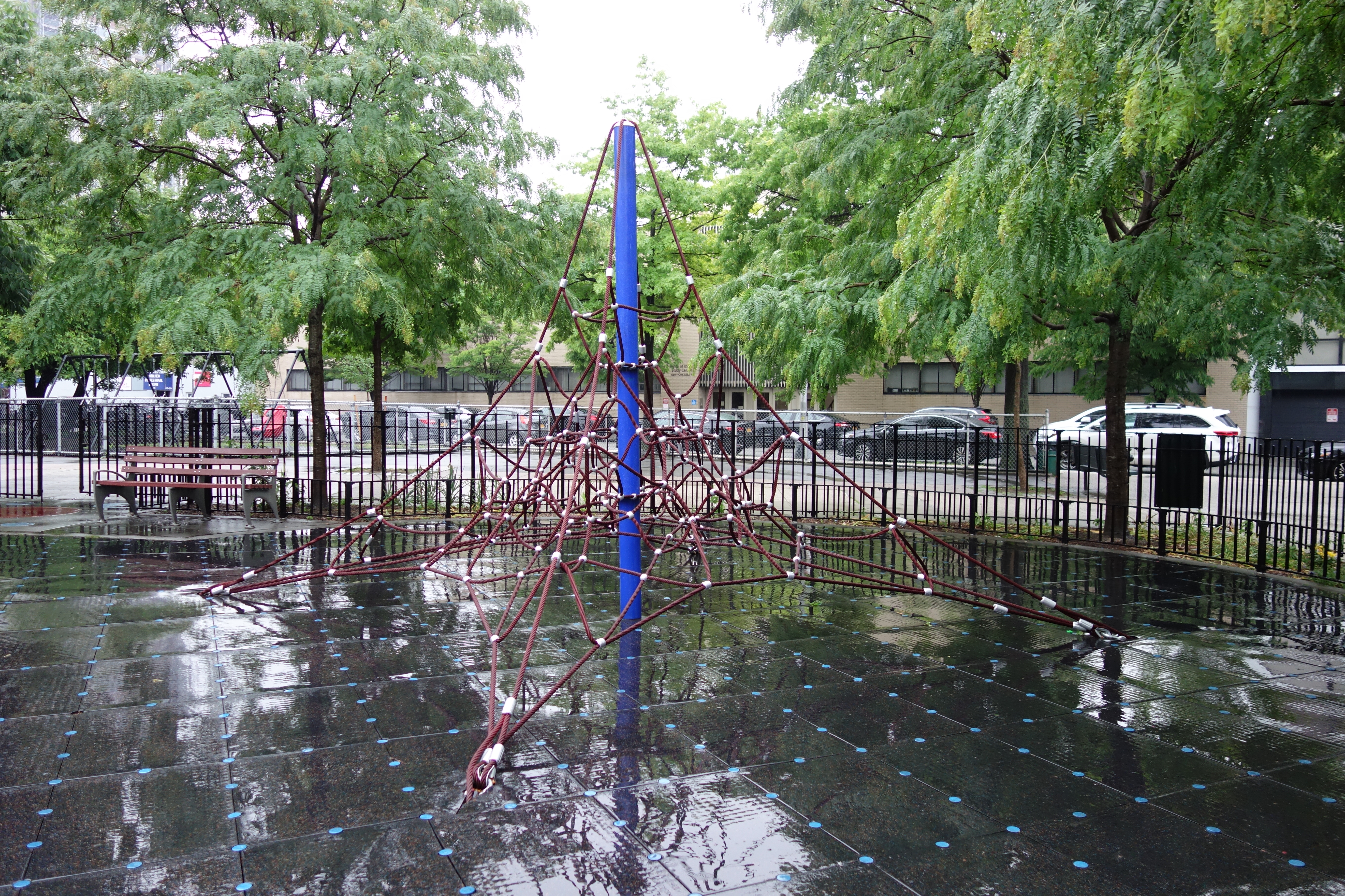 Rope-and-pole climbing structure in a fenced public park playground.