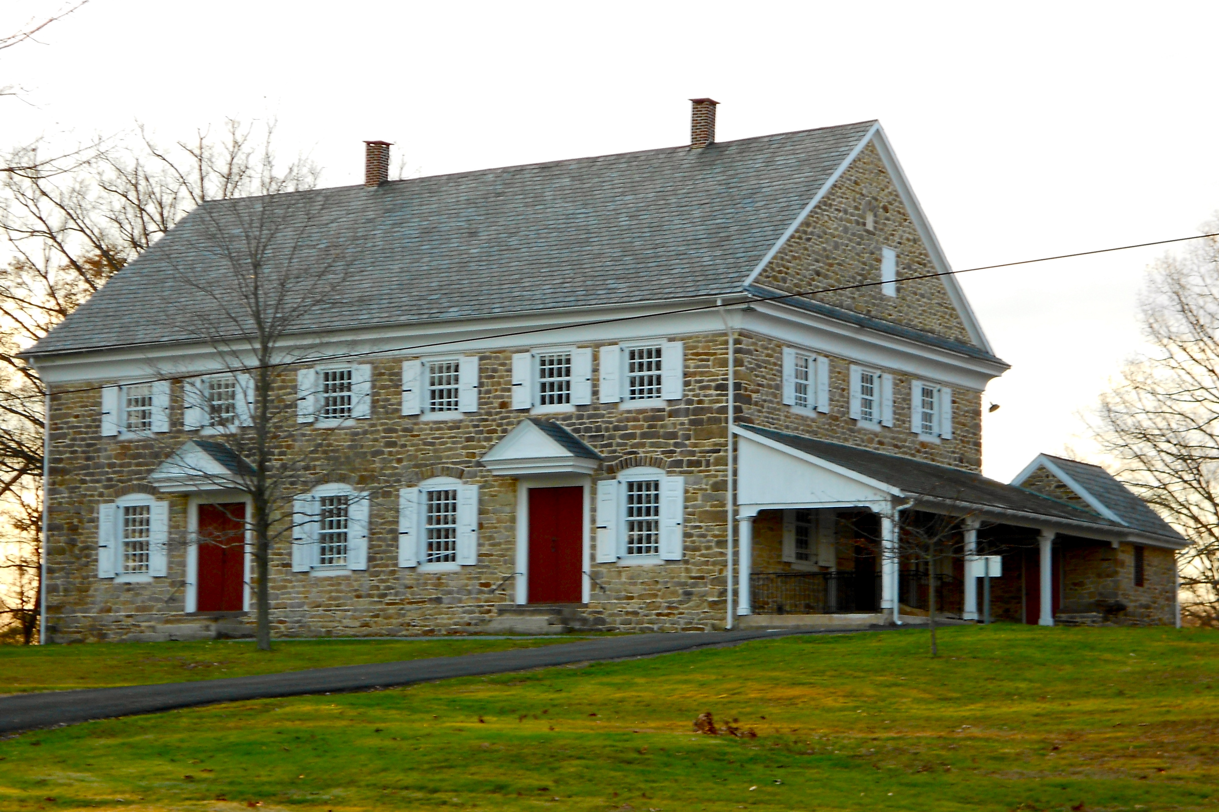 Historic stone meetinghouse with red doors and white-trimmed windows in Buckingham Township.