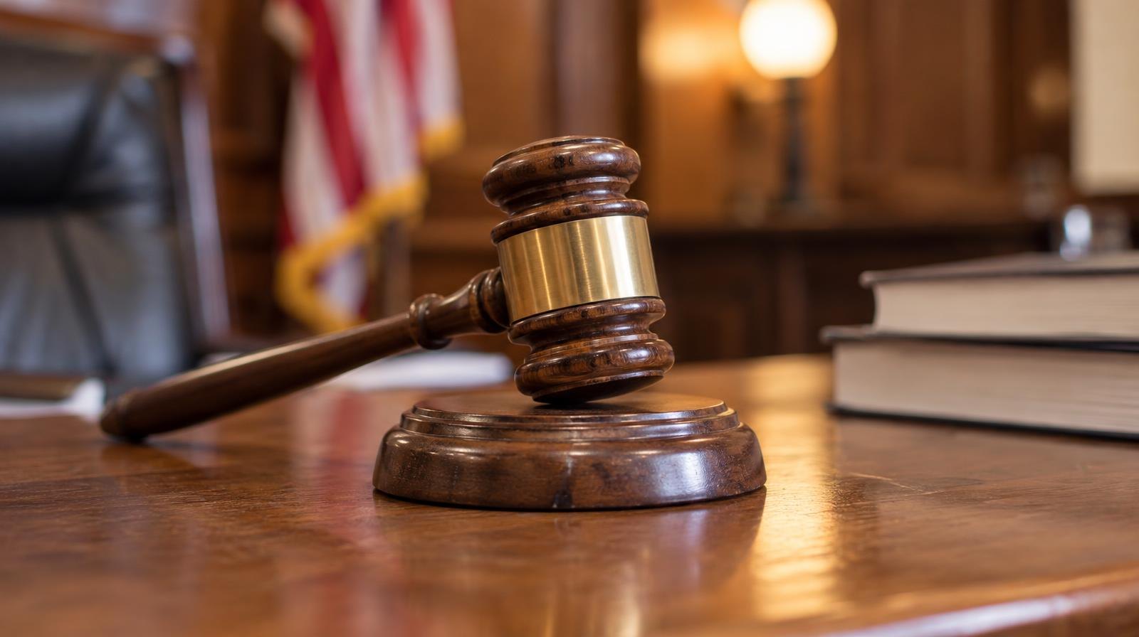 Wooden judge's gavel resting on its sound block on a polished bench.
