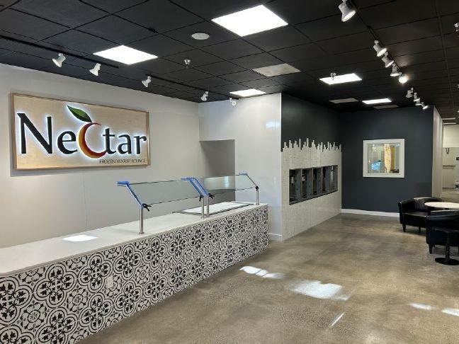 Interior of a frozen yogurt shop with self-serve machines, a tiled counter, and track lighting.