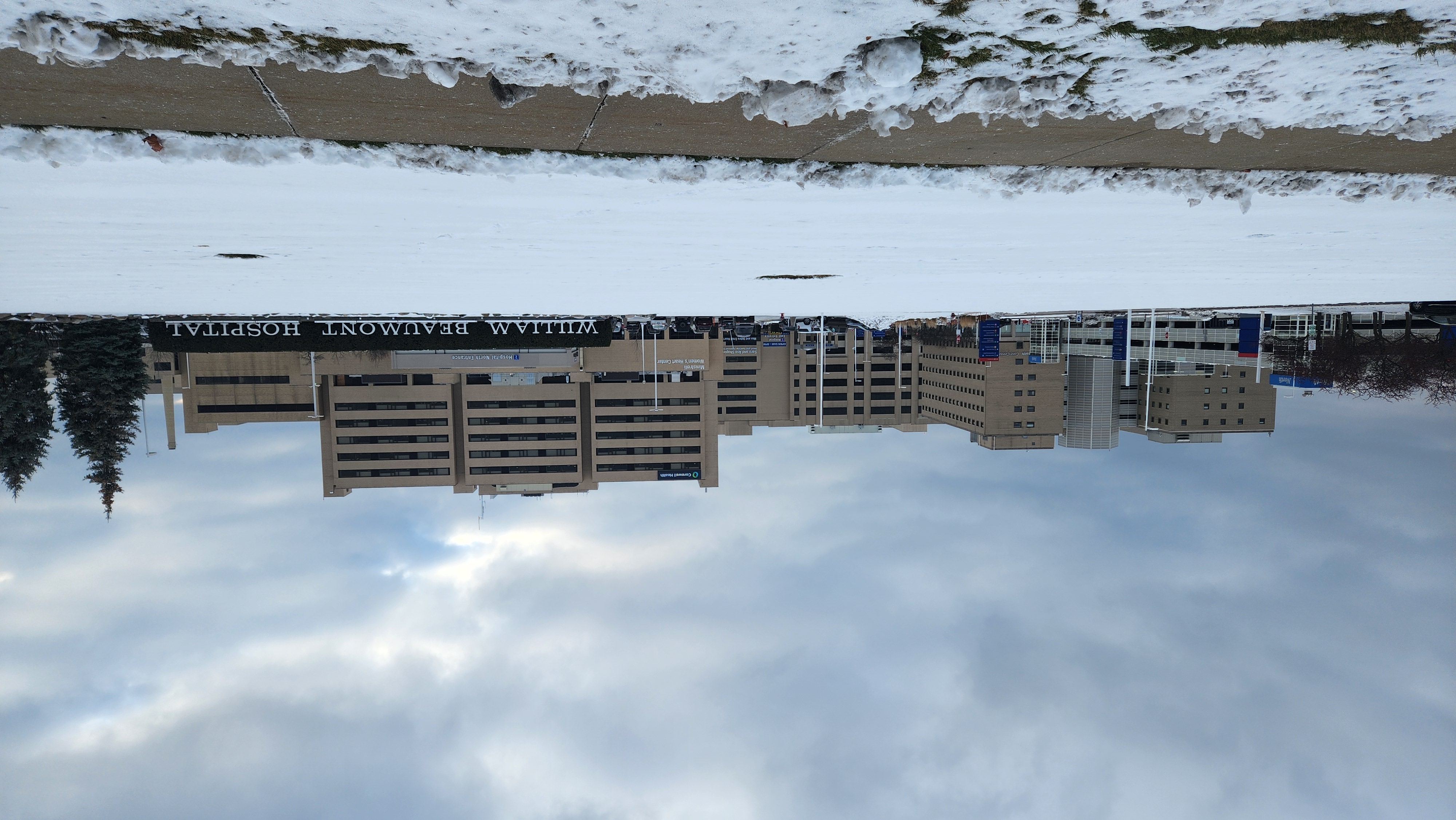 Large multi-story hospital building with signage, surrounded by snow-covered grounds.