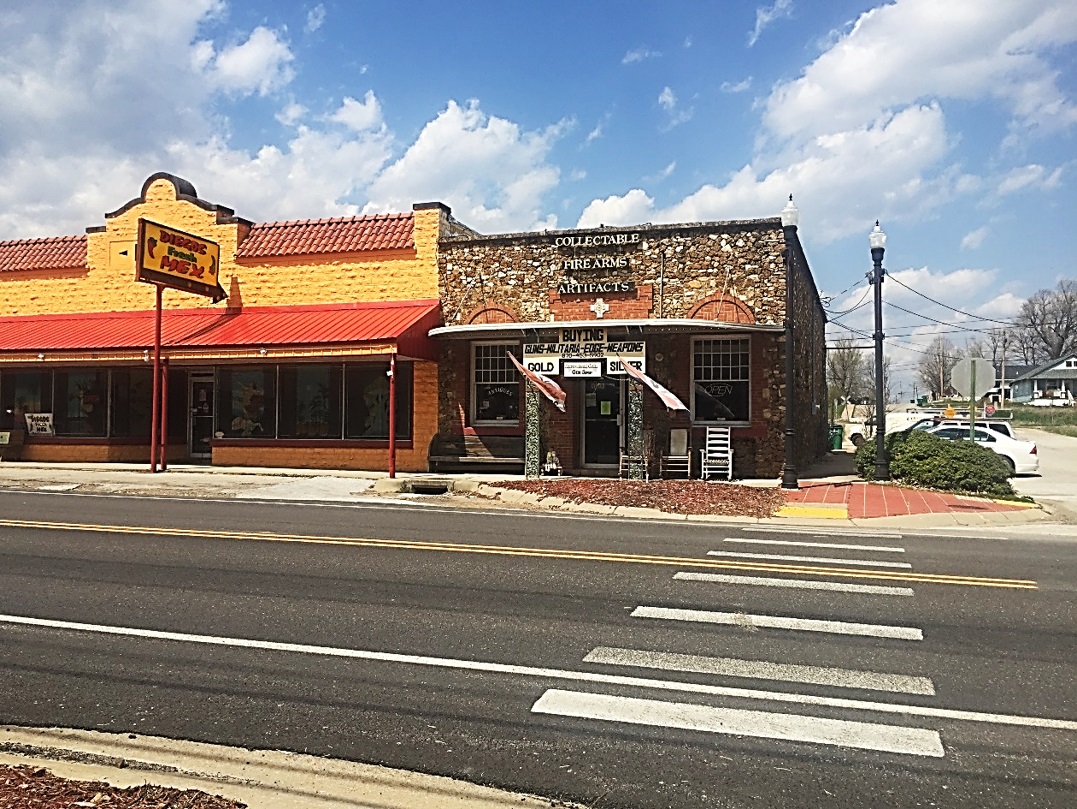 Small-town commercial street with two storefronts, a crosswalk, and parked cars.