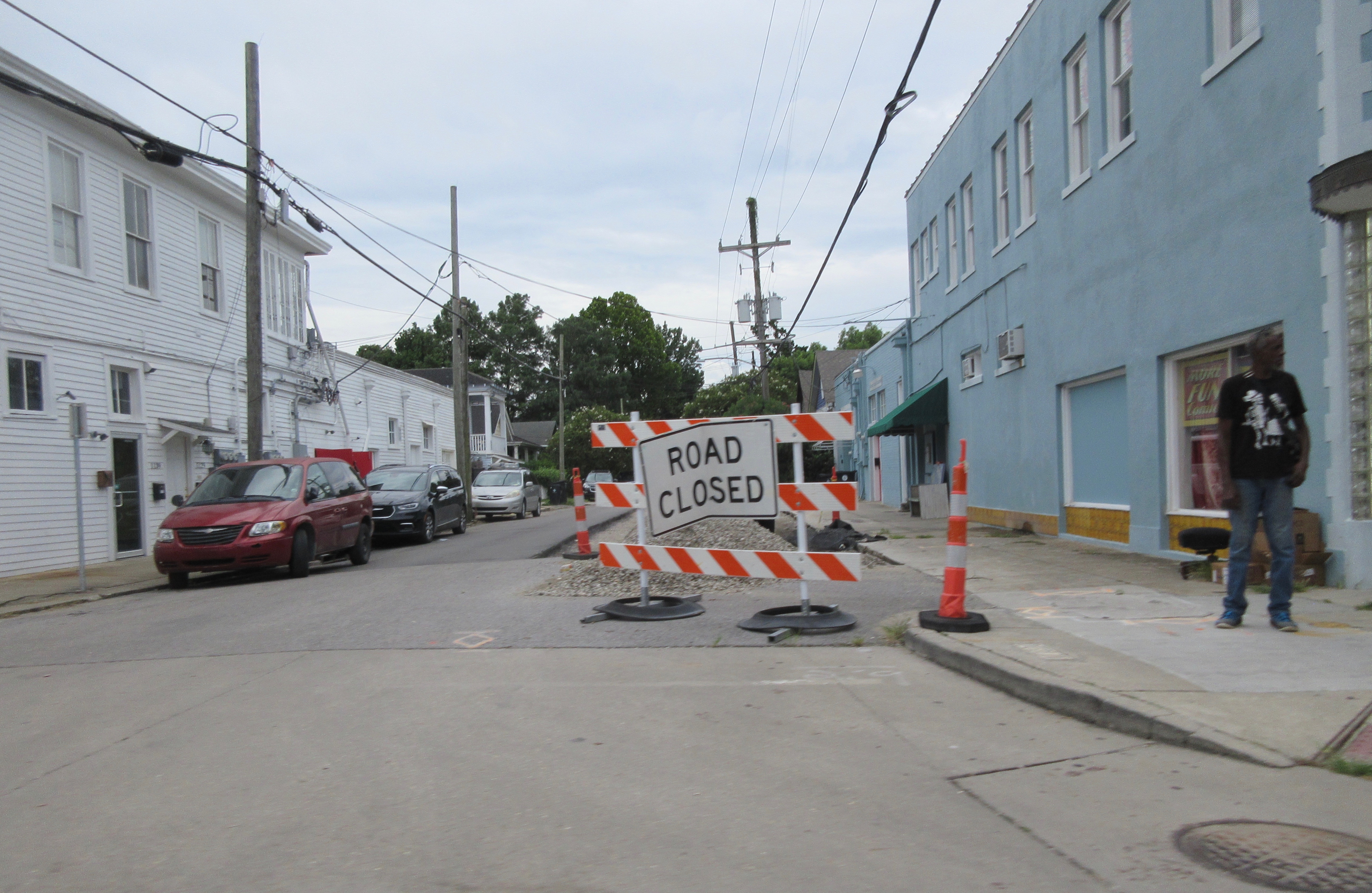 Orange Road Closed barricade and traffic cones blocking a residential street with disturbed pavement.