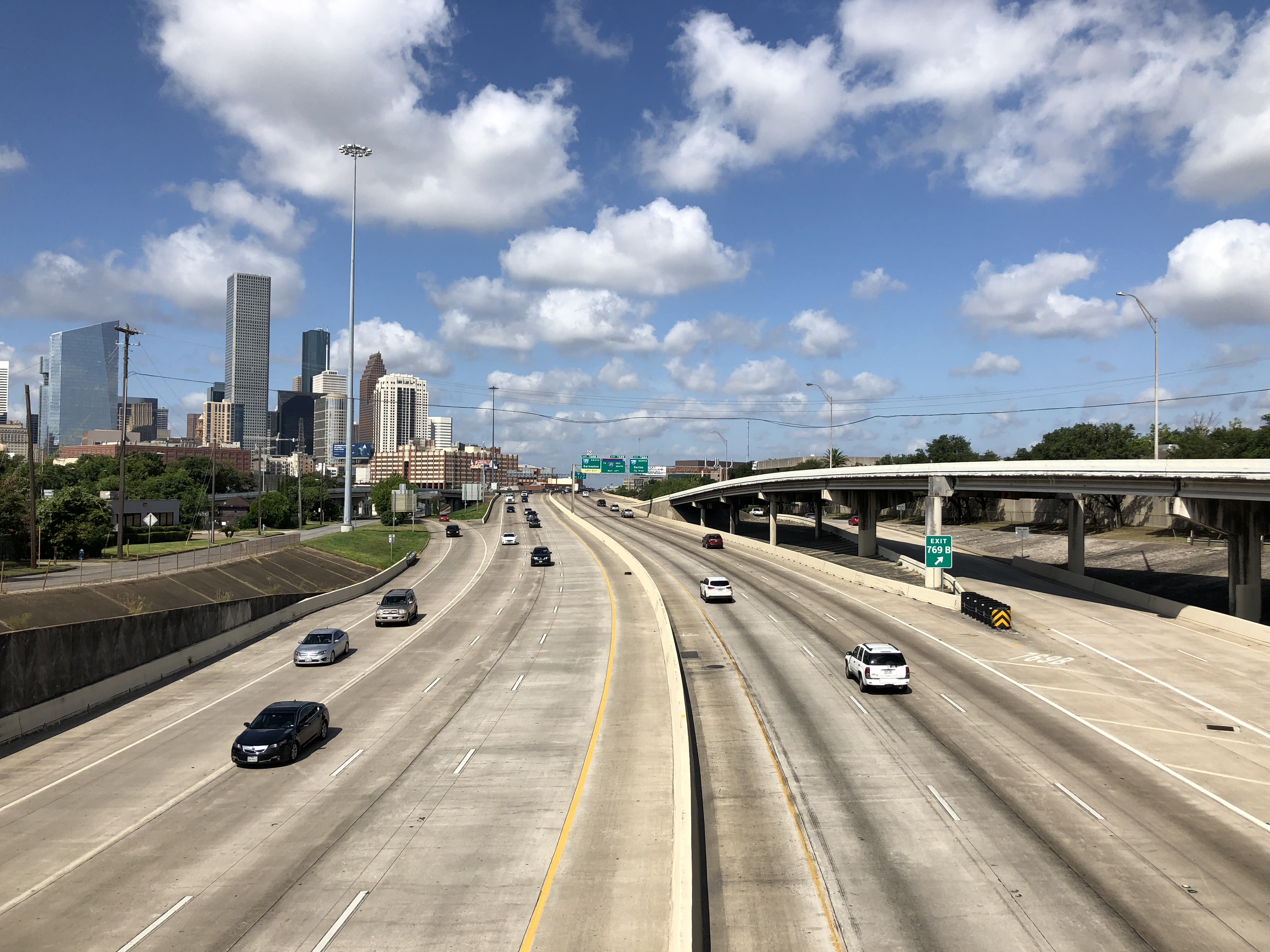 Westbound Interstate 10 freeway lanes with Houston skyline visible in the distance.